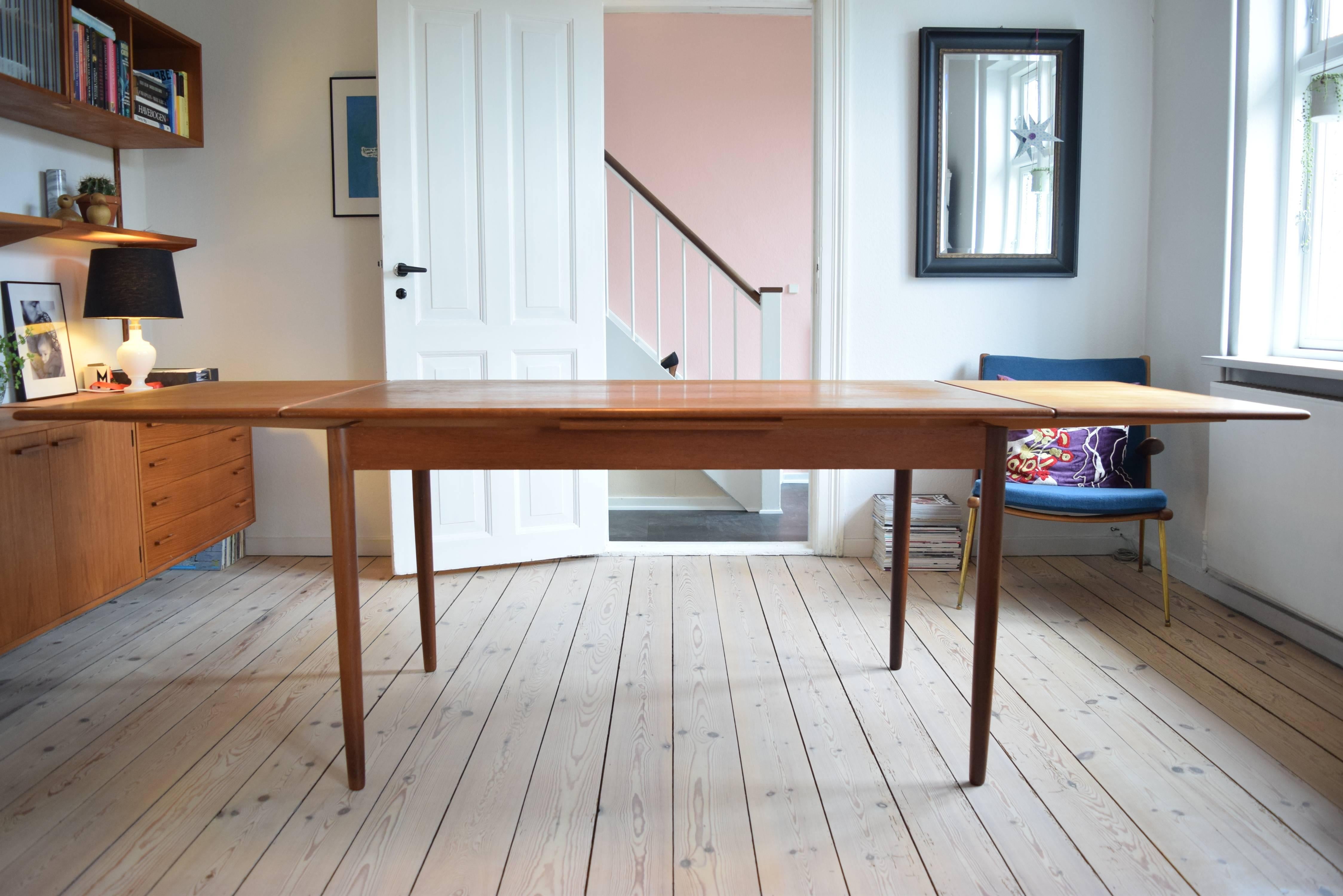 Teak dining table manufactured in Denmark in the 1960s. Features two hidden plates which when used extends the table to 240cm in length. Solid teak bevelled edge. Structurally sound with few marks and no damage.