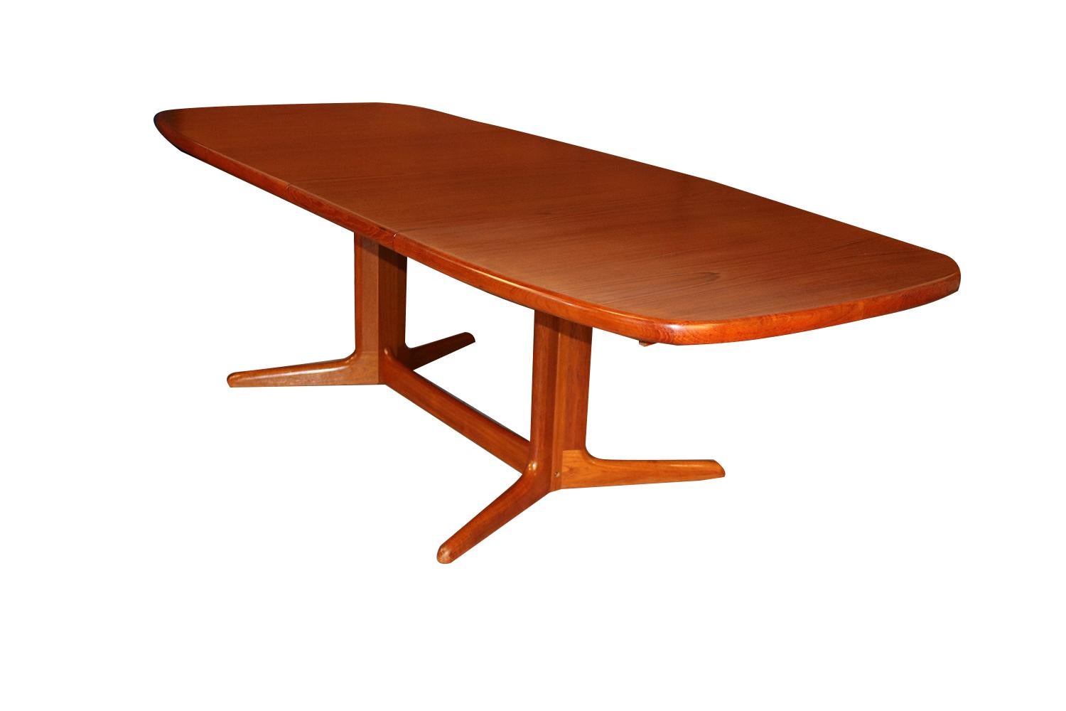 Beautiful Mid-Century Modern expandable dining table, circa 1970s. Featuring richly grained, gleaming teak and smooth, clean lines characteristic of Classic Danish design. This remarkable dining table comes with two extension leaves to accommodate