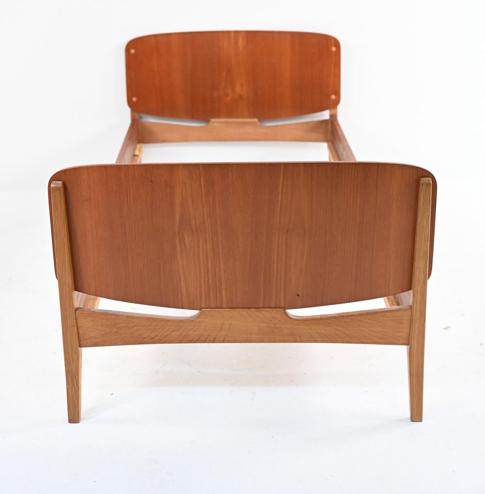 A classic Mid-Century sculptural daybed in teak-veneered mahogany and white oak, with head- and footboards of equal height; in the manner of Hans Wegner or Borge Mogensen. 