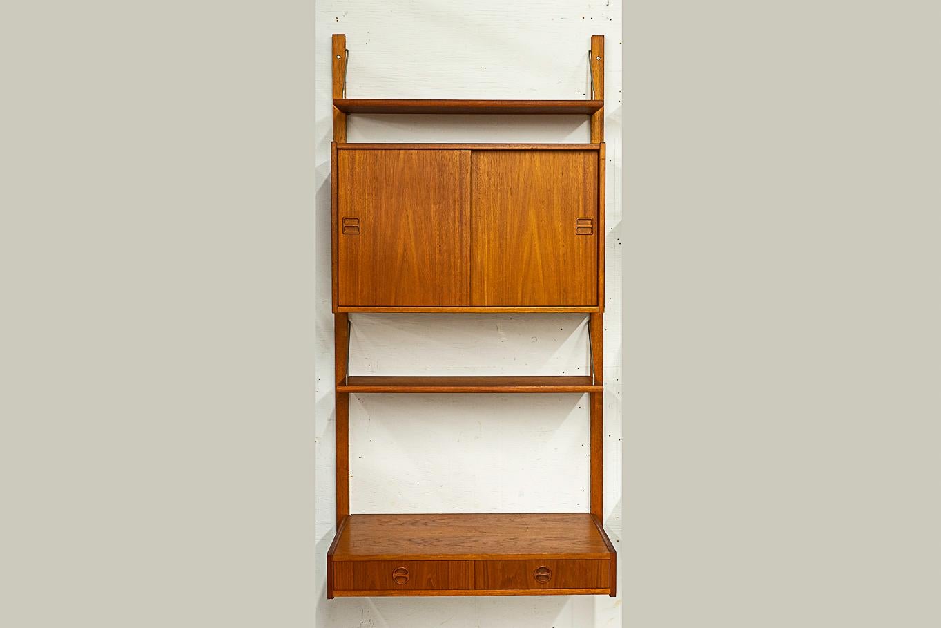 Danish Mid-Century teak wall system, circa 1960's. Fantastic wall system with solid wood trim, stunning book-matched veneer surfaces and dovetail construction. Modular design, hang it any way you like! Includes: sliding door cabinet, desk with