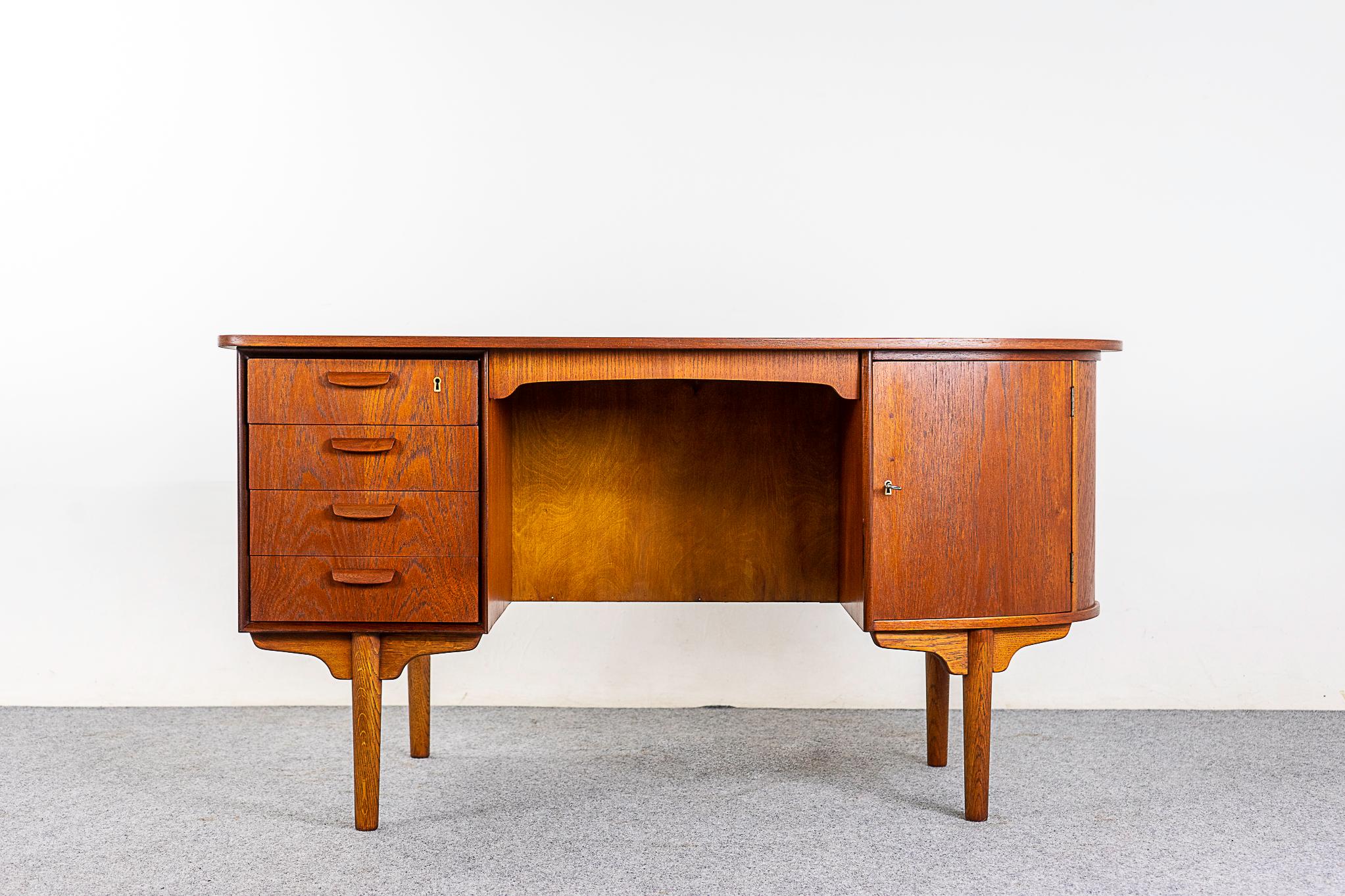 Teak asymmetrical desk, circa 1960s. Unique curved top, a nice change from the basic rectangle! Locking rounded front & rear storage cabinet with pass through drawer and 2 shelves, get organized. Beautiful dovetailed drawers with stunning grain