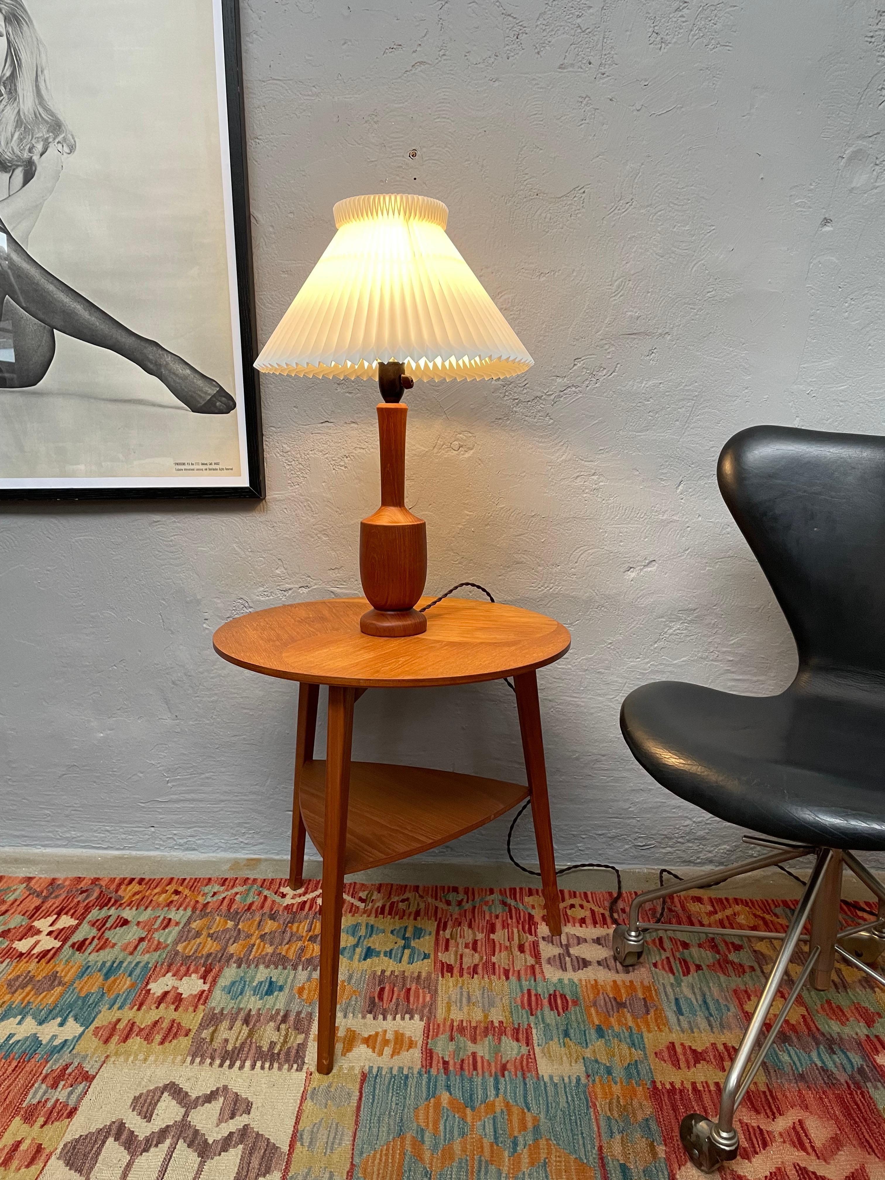 Danish mid century turned teak table lamp by Fog and Morup . 
Solid turned teak topped off with an original white plastic pleated lampshade. 
One small age related crack in the teak where the flex enters the lamp. 
Can be seen on the picture.
Of no