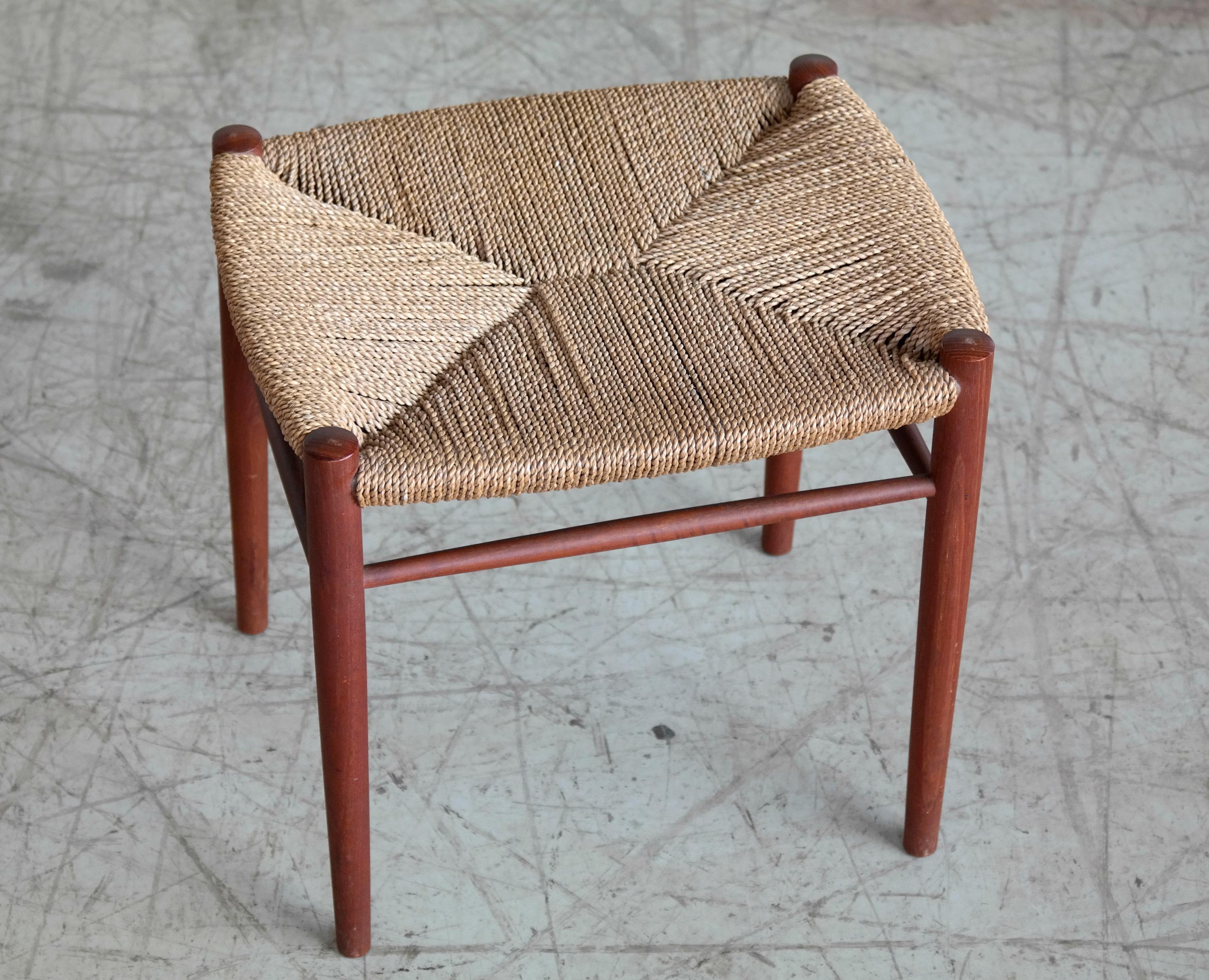 Beautiful classic Danish midcentury vanity stool in solid teak with a rush seat of spun paper cord. Made sometime in the 1950s in Denmark designer and maker unknown. Nice silhouette and paper cord in very good condition with no breaks or repairs.