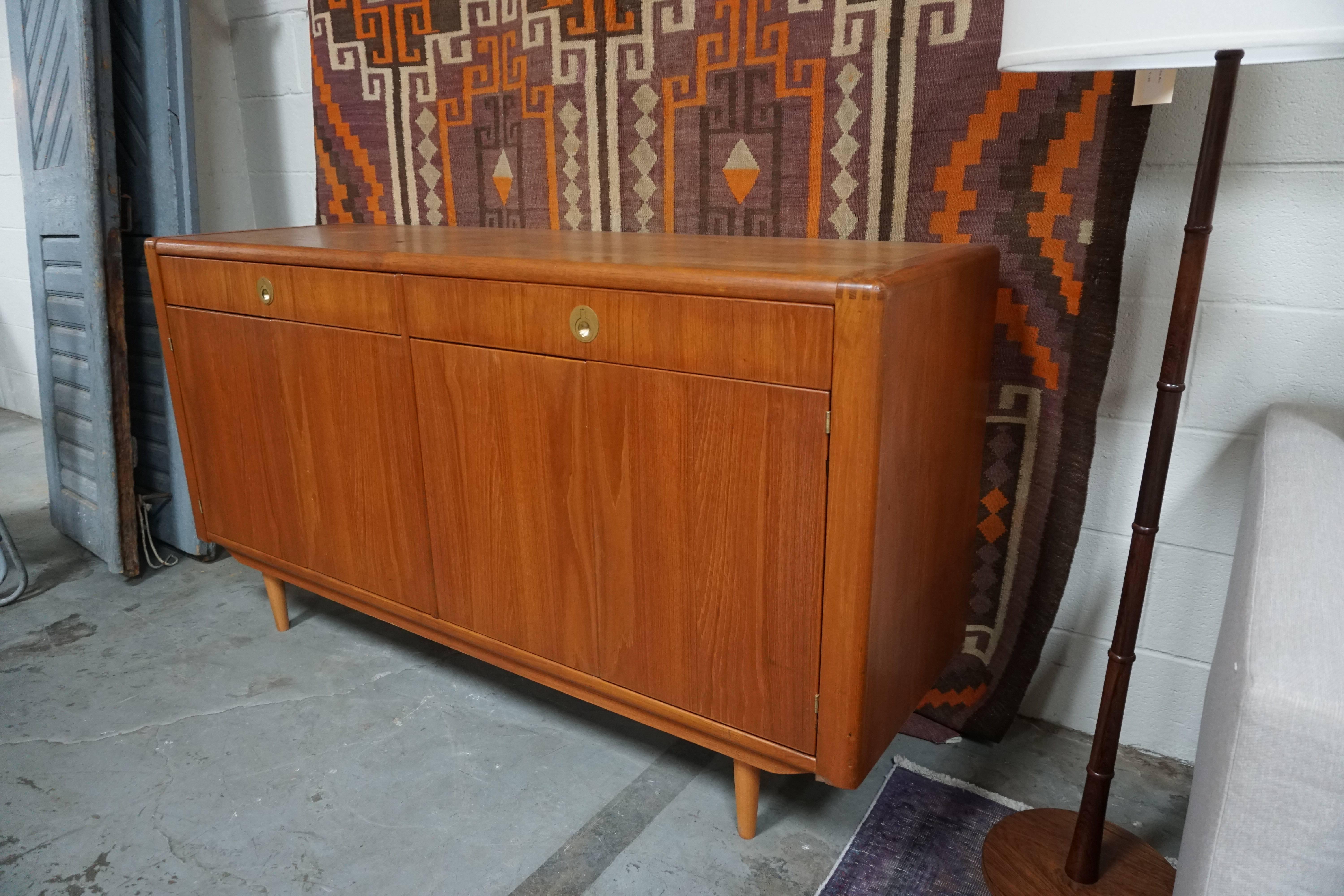 Beautiful Danish midcentury stained walnut credenza with operable doors and cabinets. With original brushed brass hardware and push latches at cabinet doors. Features rounded finger joints at corners and pencil legs.