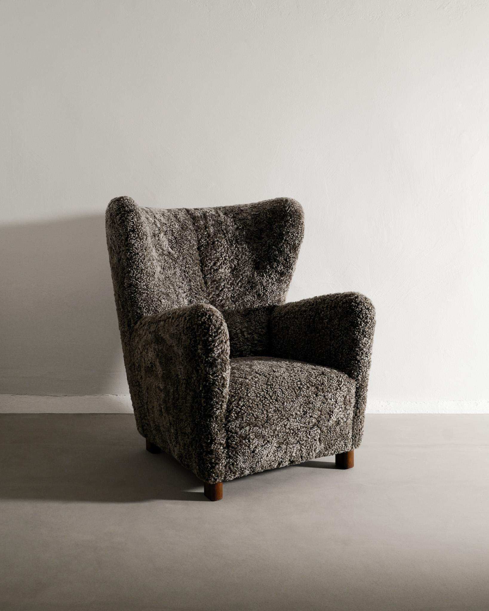 Rare fauteuil à dossier haut danois du milieu du siècle produit par Thorald Madsen Snedkeri au Danemark dans les années 1940. En très bon état et entièrement restauré et tapissé en peau de mouton couleur moka foncé par nos soins. La lampe sur la