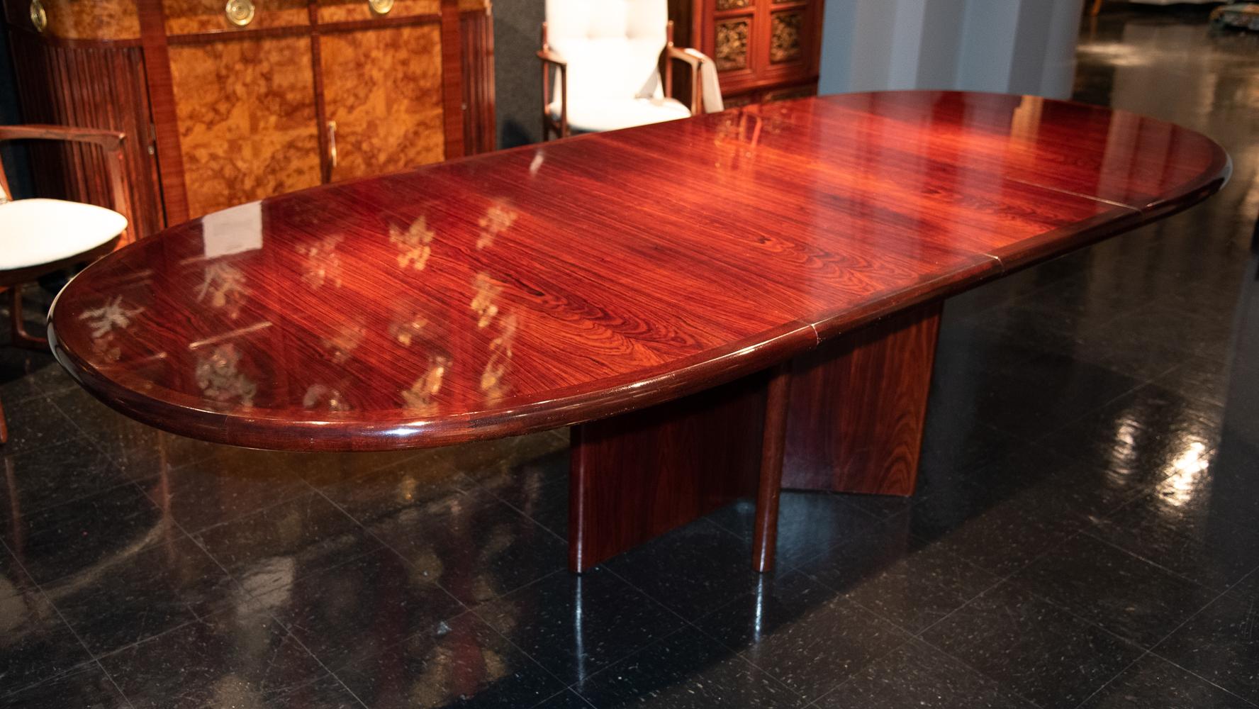 A danish mid-20th century dining or conference table in rich grained rosewood.

The Table features and oval-shaped top with two extensions leaves; raised on a pedestal base designed with six supports extending from floor-to-top of table in