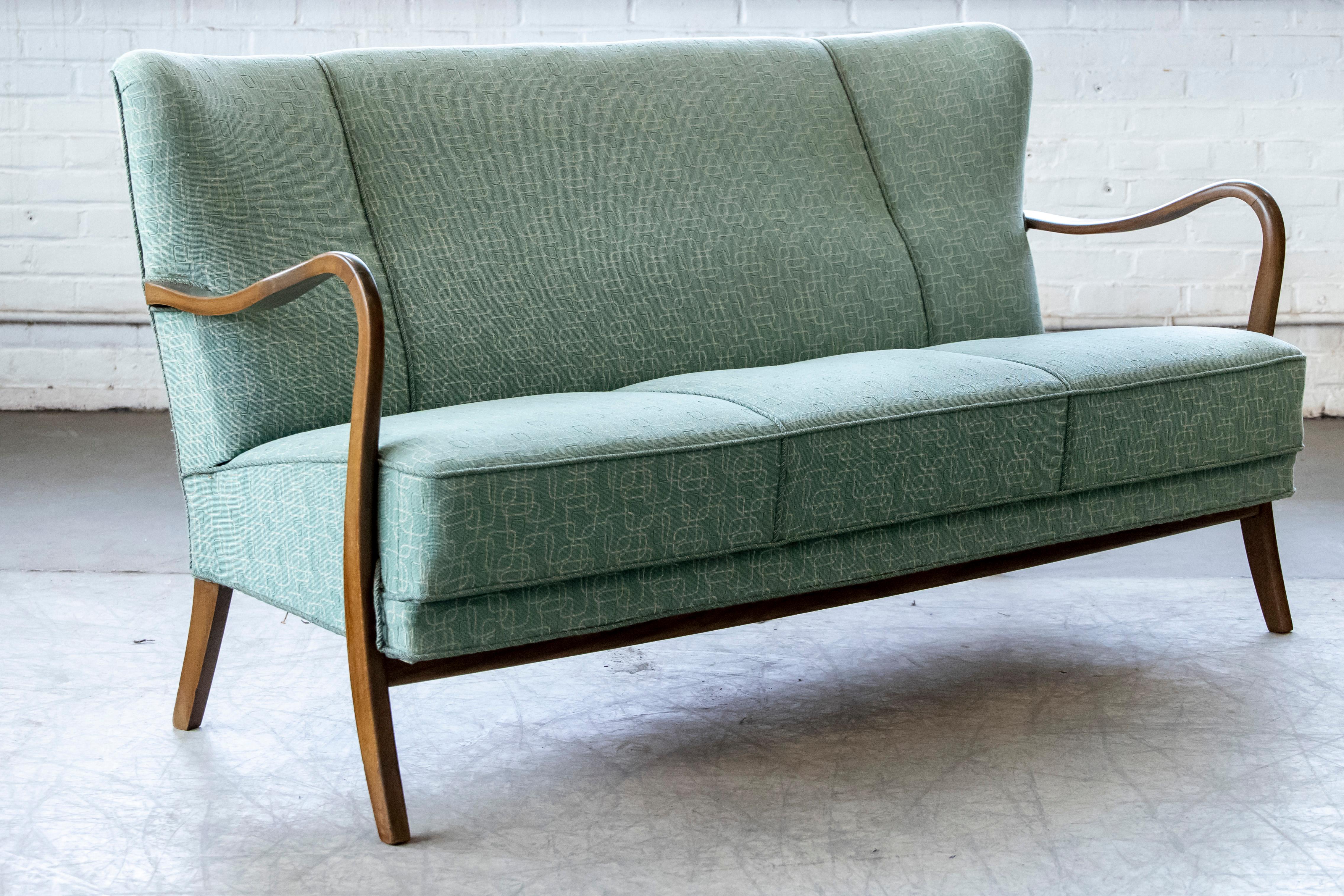 Fantastic 1940s Alfred Christensen designed sofa in his characteristic style of open armrests carved from solid beech wood and made by Slagelse Mobelvaerk in the 1940s. Beautiful refined lines with curving arms that extend into the front leg. Coil