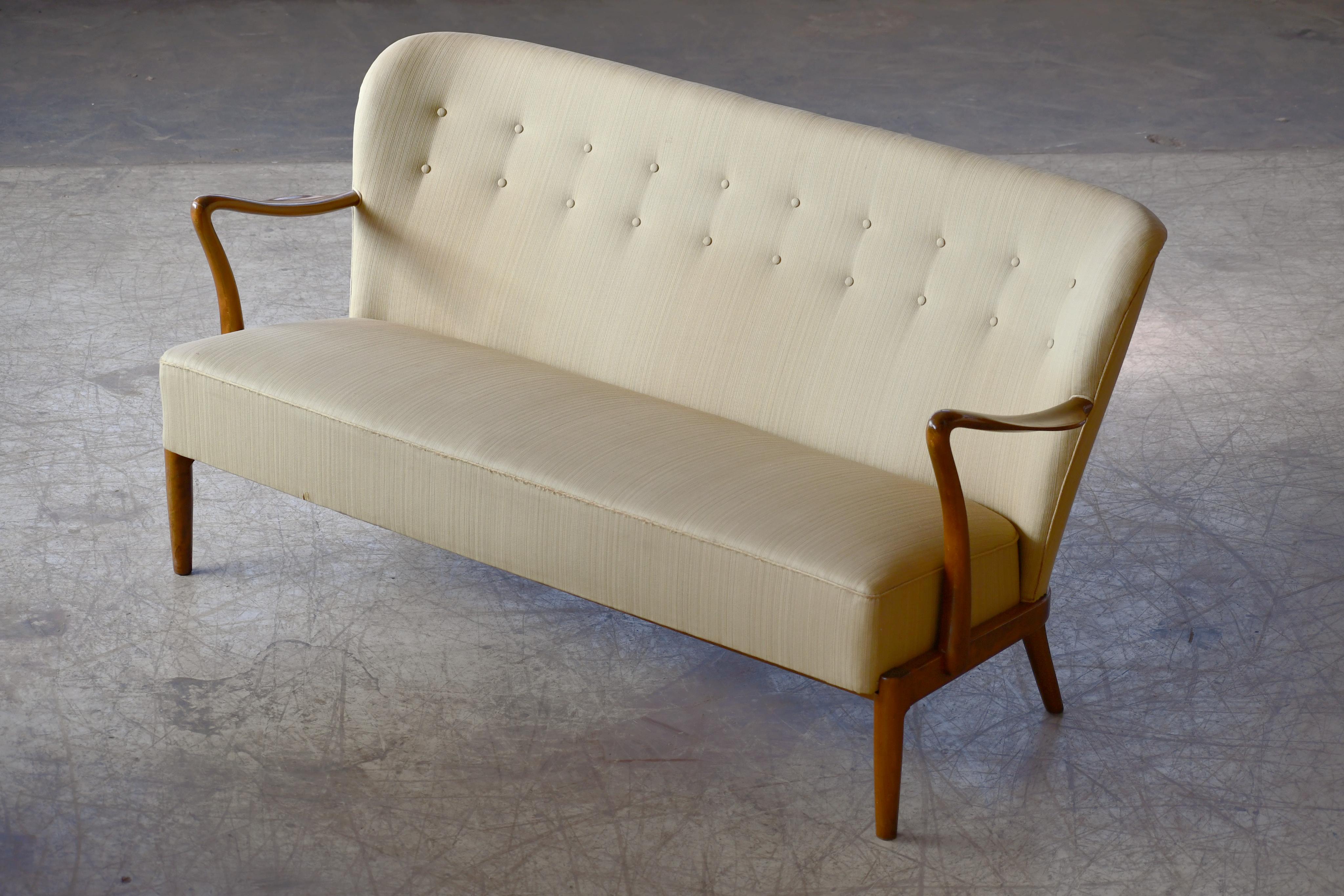 Fantastic 1940s Alfred Christensen style sofa with open armrests carved from solid beechwood in the 1940s. Beautiful refined lines with curving arms, coil springs in the seat and tufted back raised on a base of solid wood and straight legs. Some