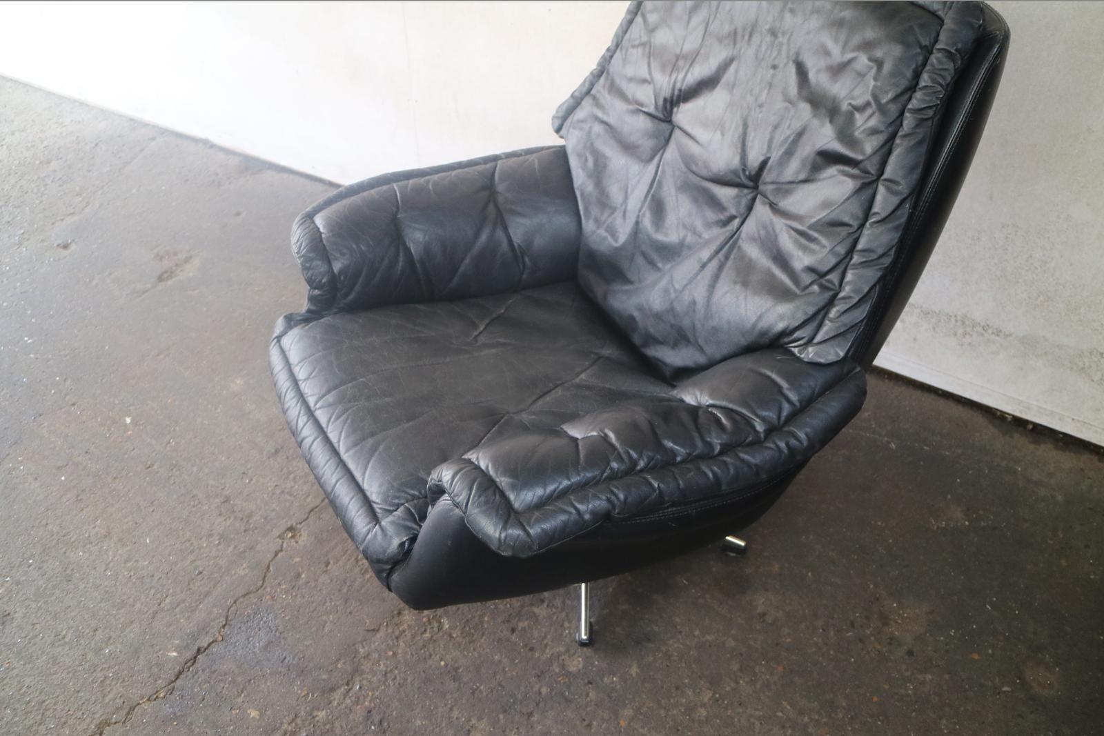 A Danish swivel all leather armchair. The upholstery is a ‘second skin’ layer that drapes over the frame. The black leather is high quality and well used.

 