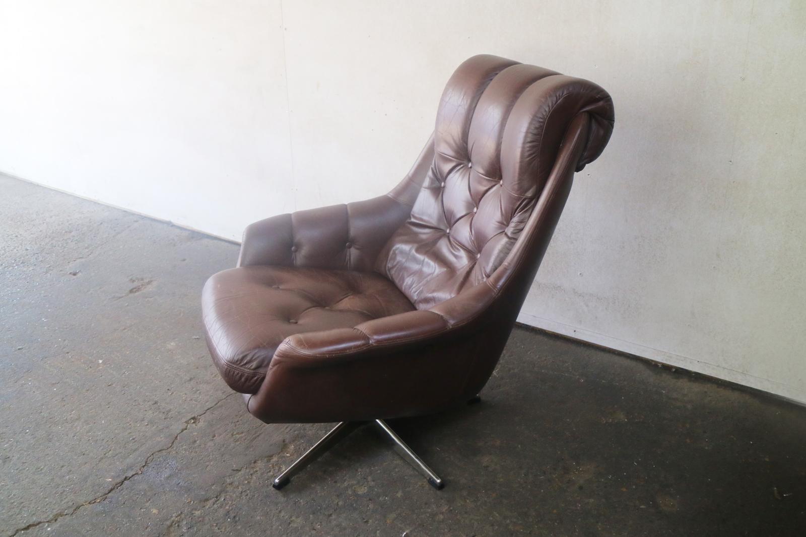 A Danish swivel brown leather armchair. It has a roll over head rest and button detailing.