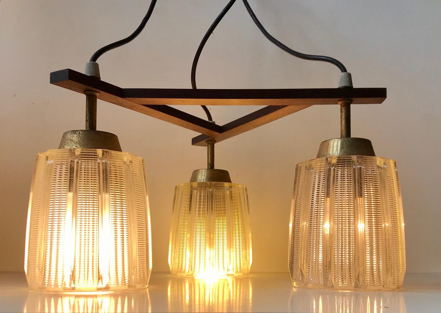 This Mid-Century Modern 3-shaded chandelier was manufactured in Denmark during the late 1950s in a style inspired by French and Italian Modernism. Beautiful glass shading in solid brass sockets/tops.