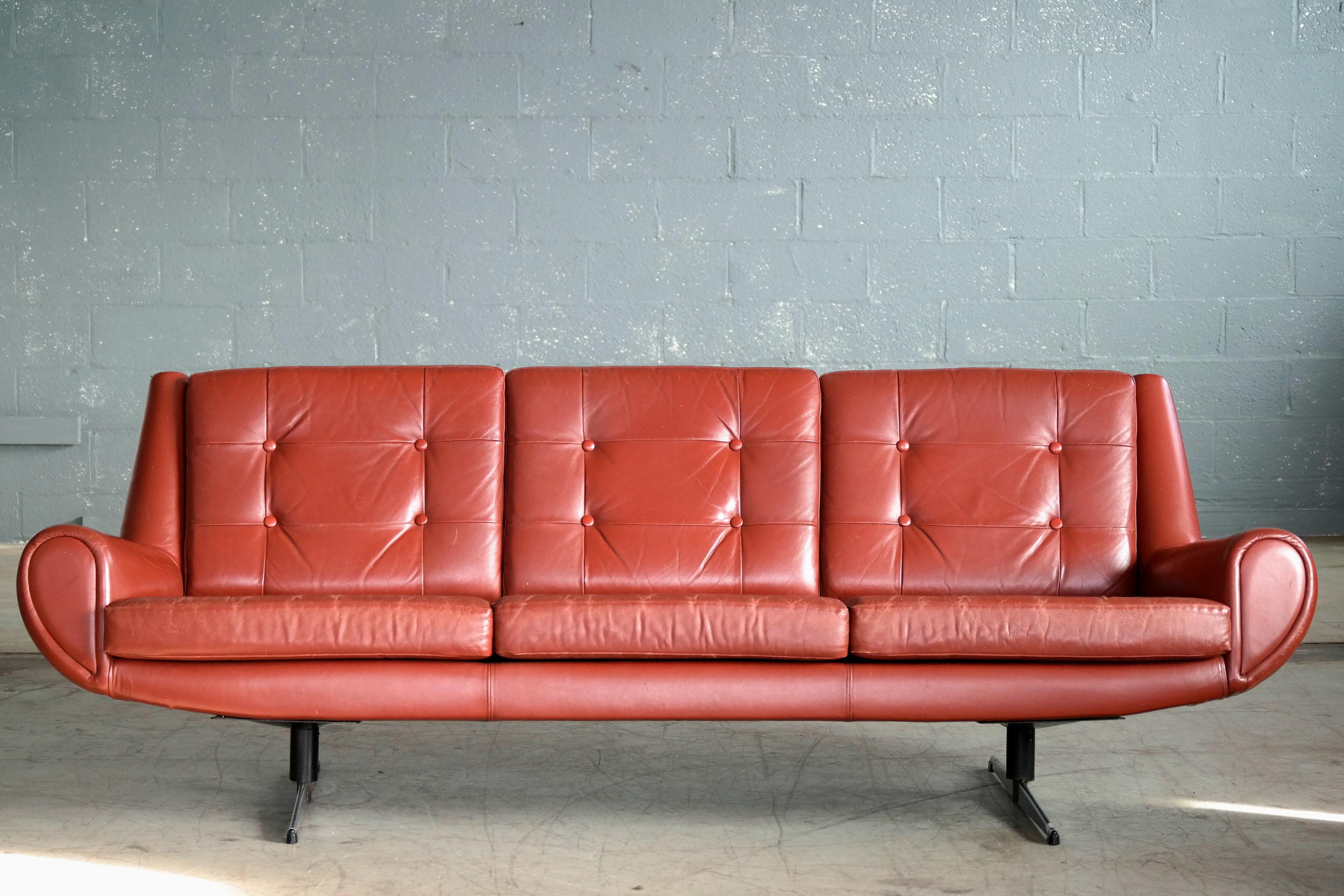 Fabulous Danish airport style sofa in cognac colored leather characteristically raised on metal legs designed by Skjold Sorensen in the late 1960s. We love the rounded edges and thick armrests which was ahead of its time in the 1960s. We have
