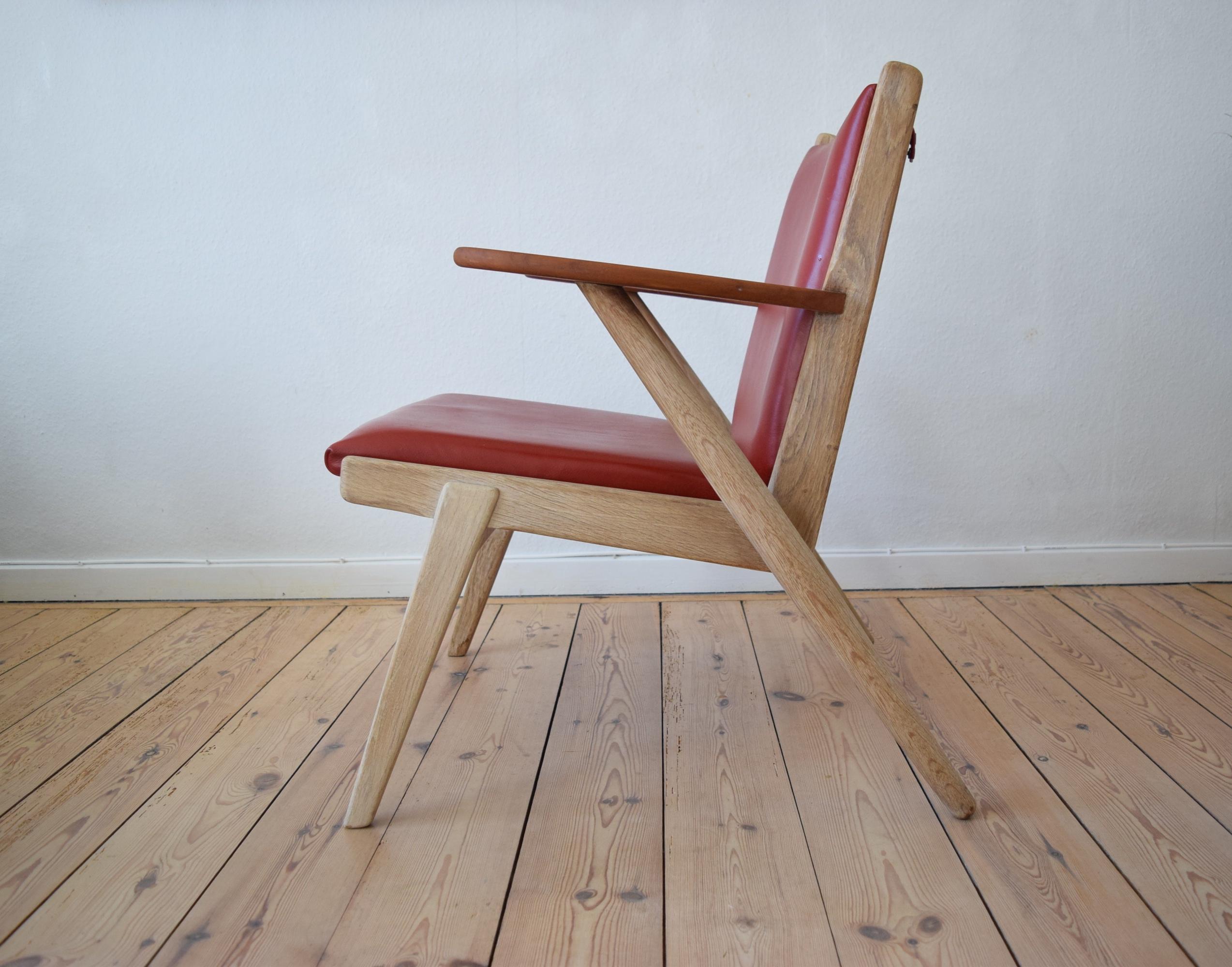 Midcentury Danish teak lounge chair designed by Arne Wahl Iverson for Hans Hansen & Sons, Odense. This chair is in oak with teak paddle armrests and are covered in soft red aniline leather. Reminiscent of similar designs by Hans Wegner (Cigar Chair)