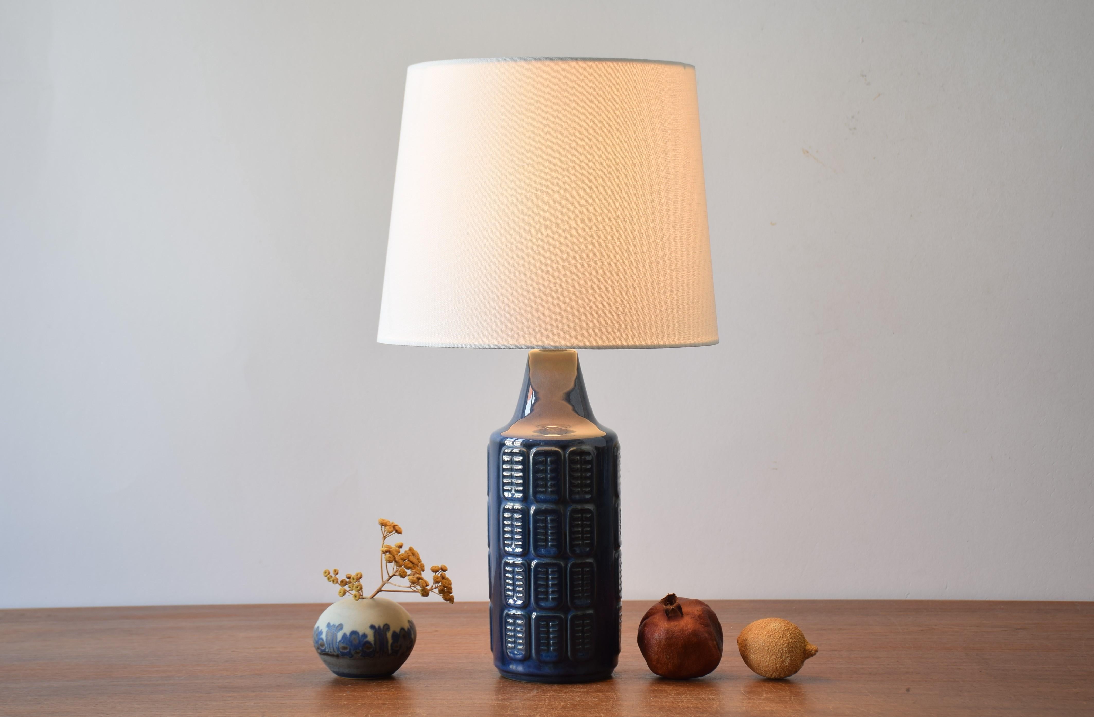 Table lamp by Einar Johansen for Søholm Stentøj, Denmark, circa 1960s.
The lamp has shiny blue glaze with purple elements over an embossed repeated graphic decor. 

Included is a new lamp shade designed and made in Denmark. It is made of woven