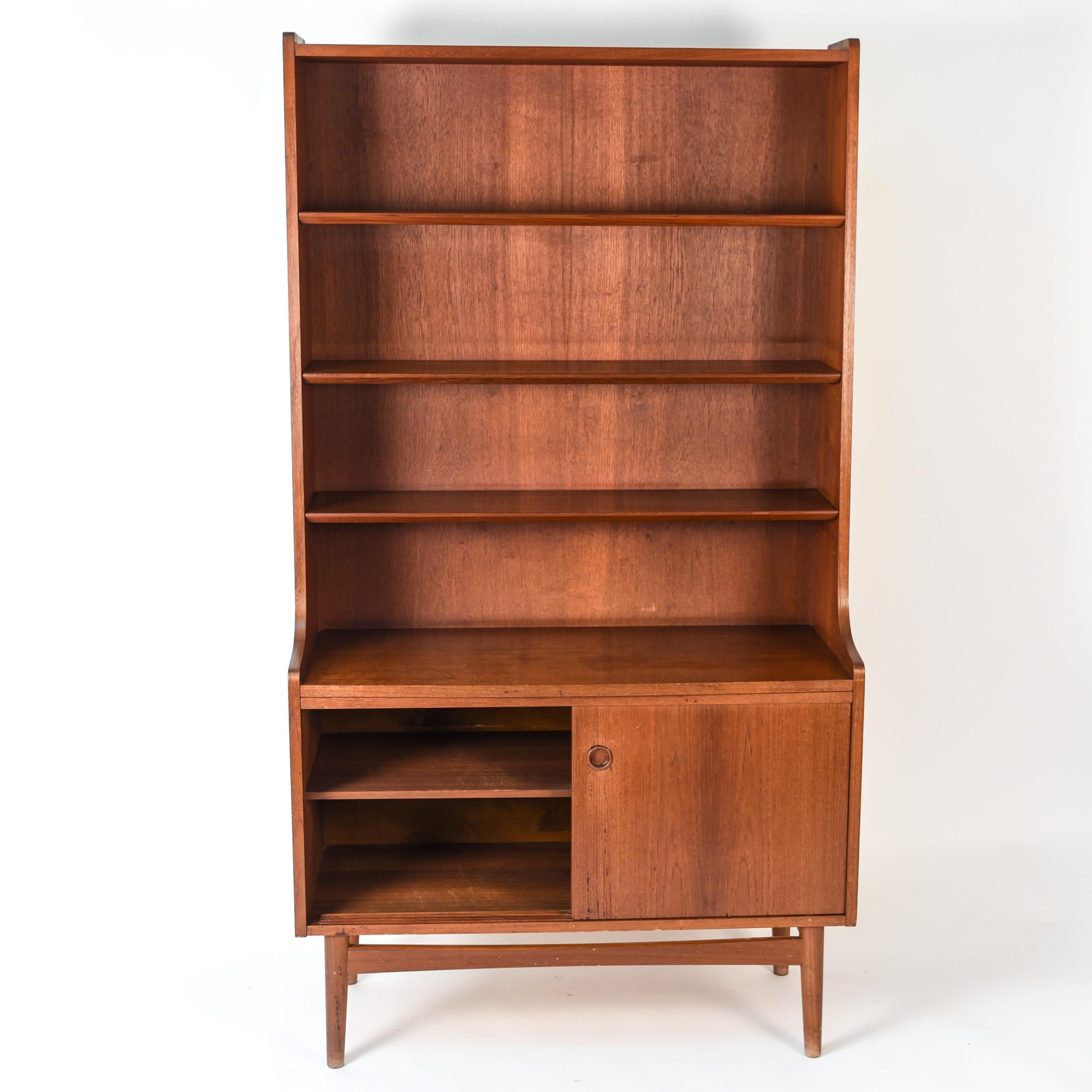 This teak bookcase or secretary was designed by Johannes Sorth for Bornholm Møbelfabrik, Nexø in the mid-1960s. The tall, upper hutch features adjustable shelves. The lower cabinet features two sliding doors which open to an adjustable shelf for