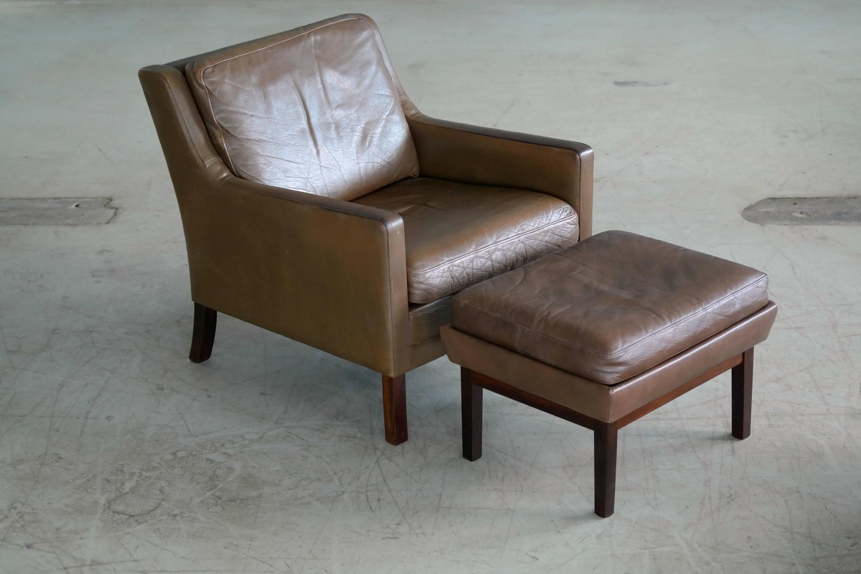 Iconic Borge Mogensen style Danish easy chair with ottoman in olive brown /green buffalo leather designed by Georg Thams in the 1960s. The thicks buffalo hide shows nice wear and patina throughout and the color has faded to show both olive green and