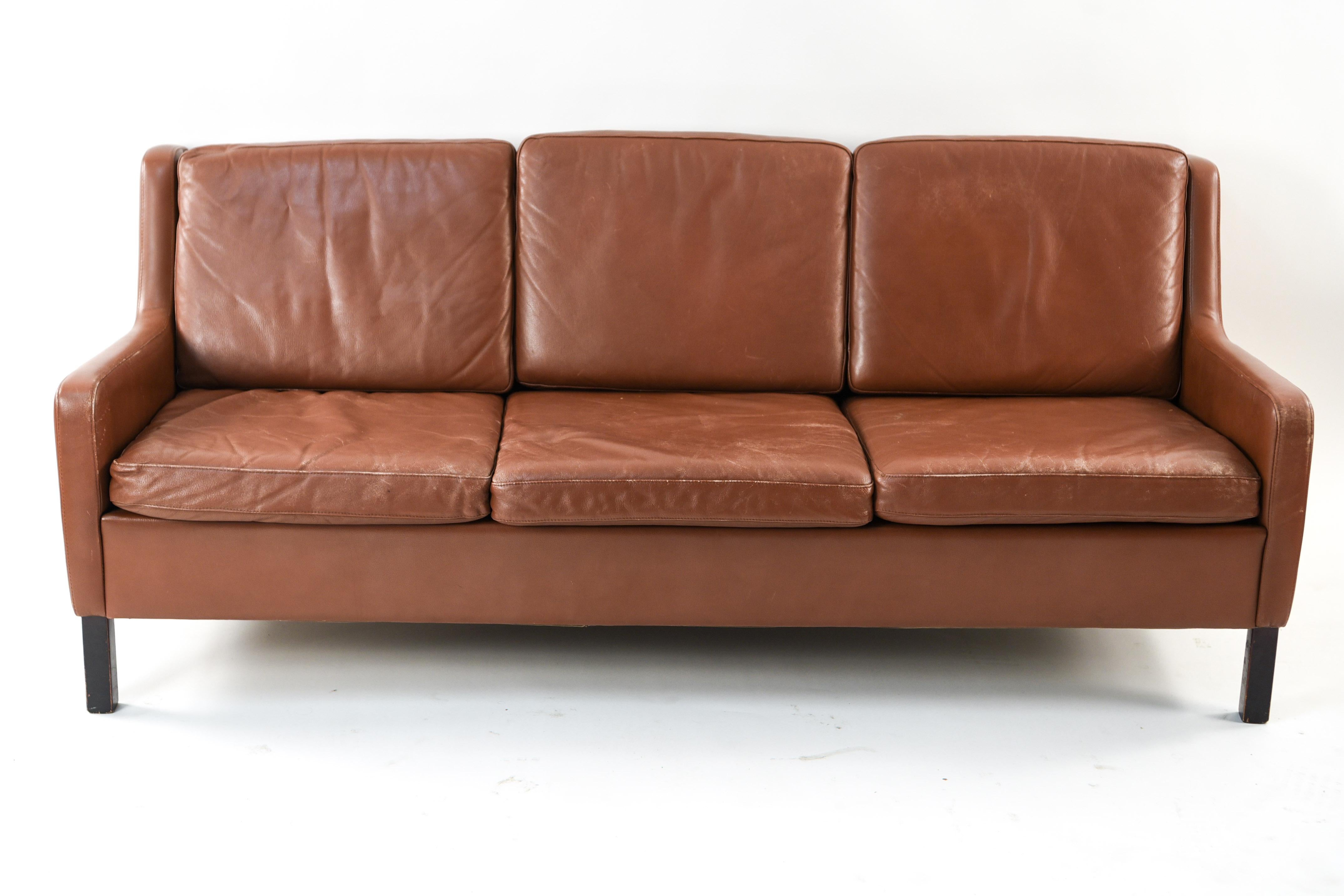 This three-seat sofa is in the manner of Danish designer Borge Mogensen. This fabulous piece is upholstered in supple, vintage leather with a wonderful patina.