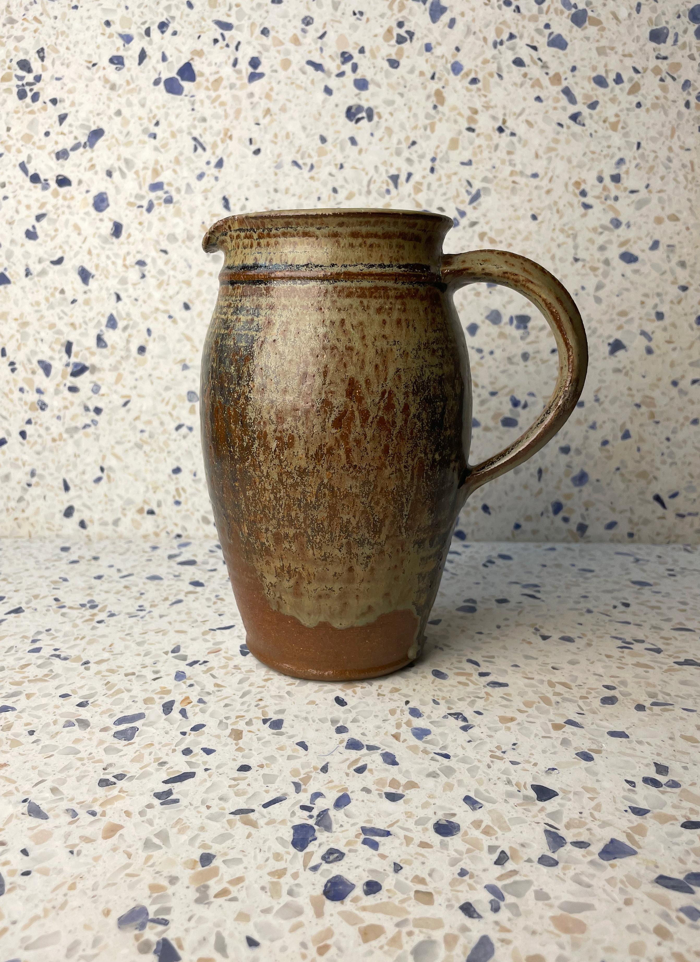 Handmade Danish modern ceramic pitcher vase with organic earth colored running glaze. Dark brown, artichoke, taupe, tan, blue and moss colors in a beautiful mix. Glazed inside and out. Raw ceramic on the base. Beautiful vintage condition.
Denmark,