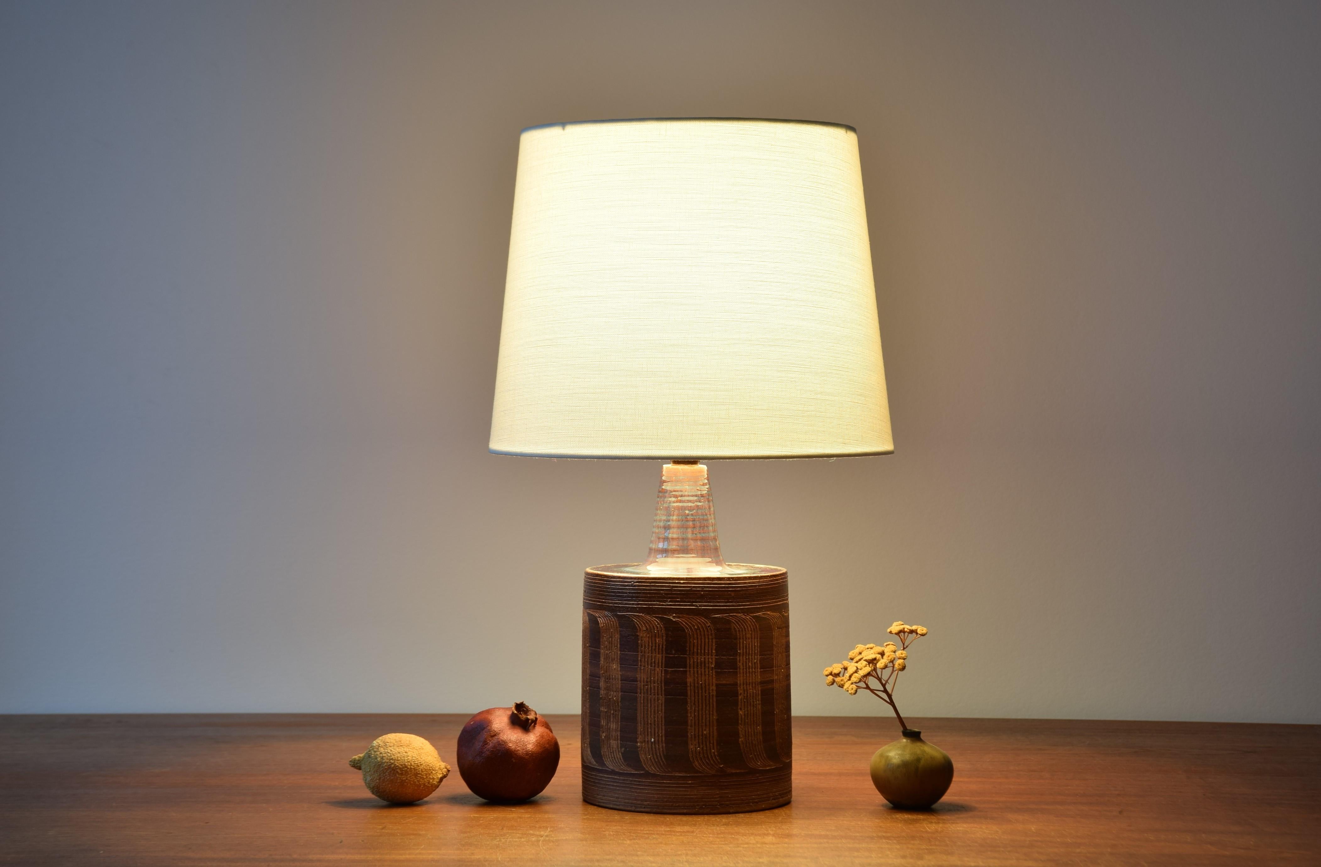 Midcentury Danish table lamp by Danish ceramist Jytte Trebbien. It´s from her own studio. Made circa 1960s. The neck and shoulders are covered with subtle glaze colors in shades of bordeaux and purple. The body is decorated with a repeated fine