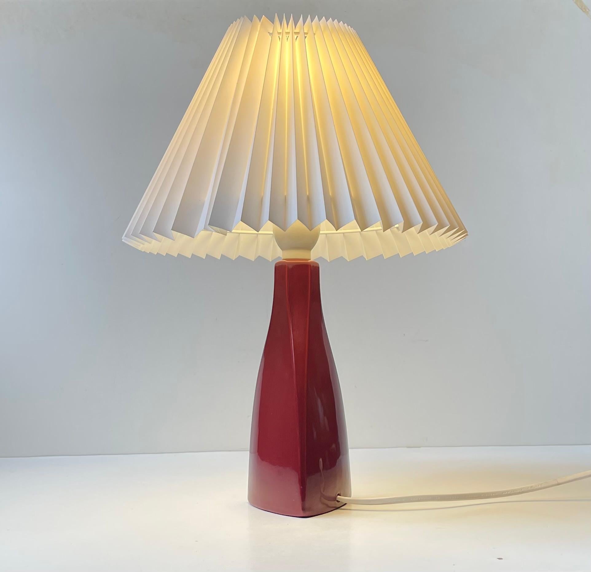 Una rara lampada da tavolo in ceramica dalla forma asimmetrica che sfoggia un vibrante e profondo vetro bordeaux/marrone. Progettato e realizzato presso la Nordisk Solar in Danimarca negli anni '70. È dotato di un nuovo paralume danese bianco