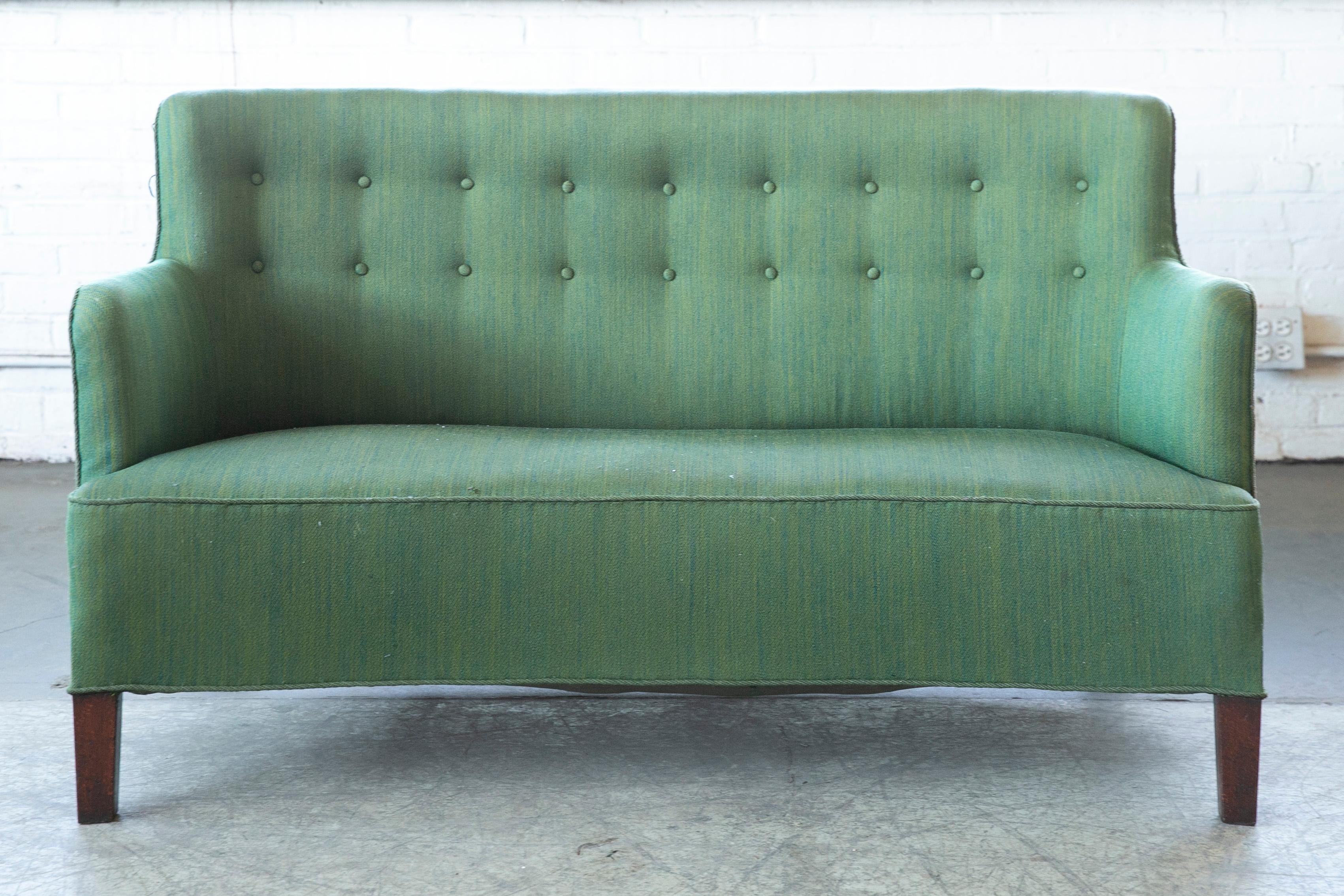 Very elegant small sofa or settee made around 1940 around Copenhagen, Denmark. it is very much in the style of Master Carpenter Georg Kofoed but Designer and maker is unknown to us. Beautiful curved shape with a short backrest and high armrests