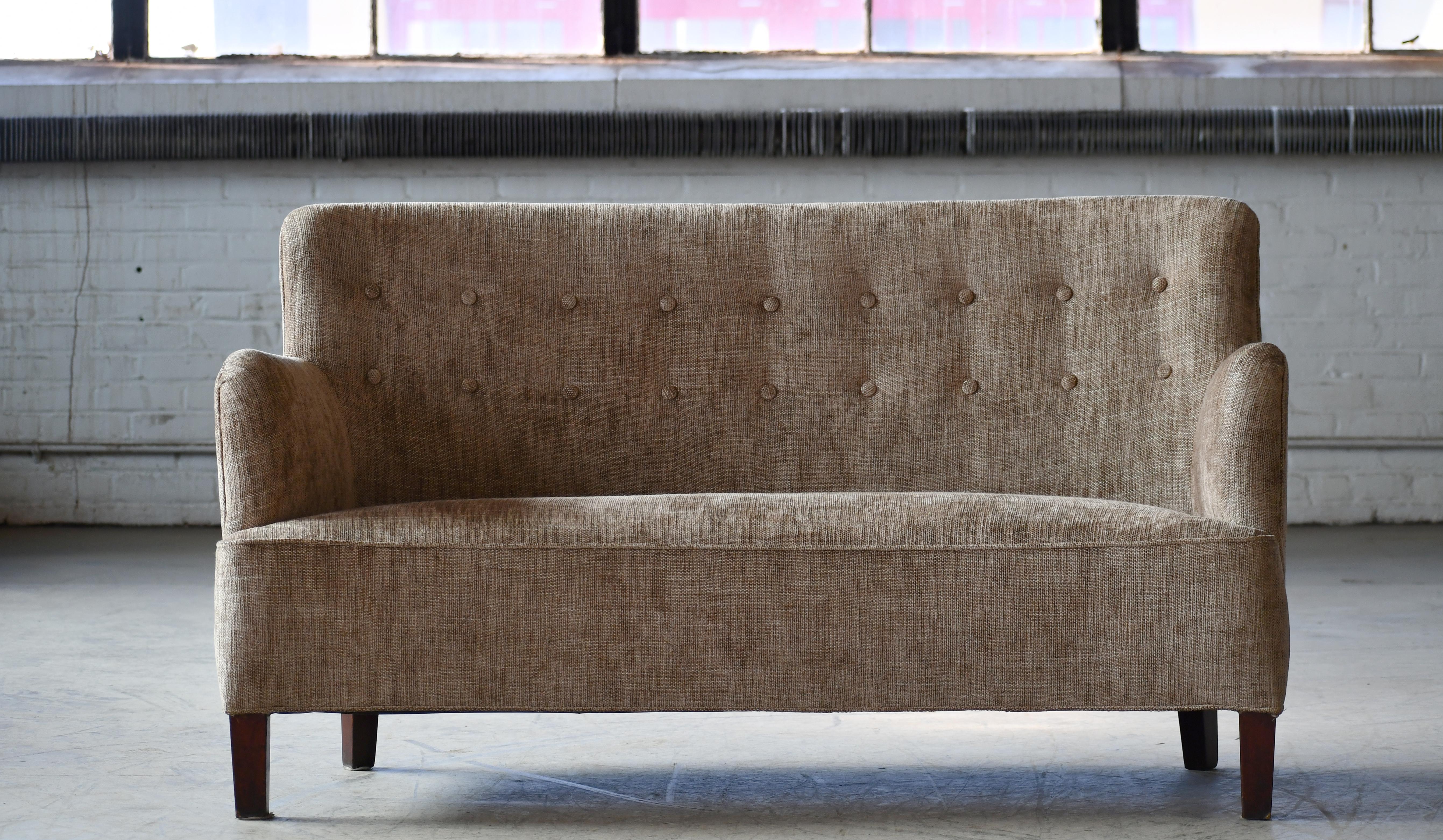 Very elegant small sofa or settee made around 1940 in Denmark. it is very much in the style of Master Carpenter Georg Kofoed but Designer and maker is unknown to us. Beautiful curved shape with a short backrest and high armrests calling for a very