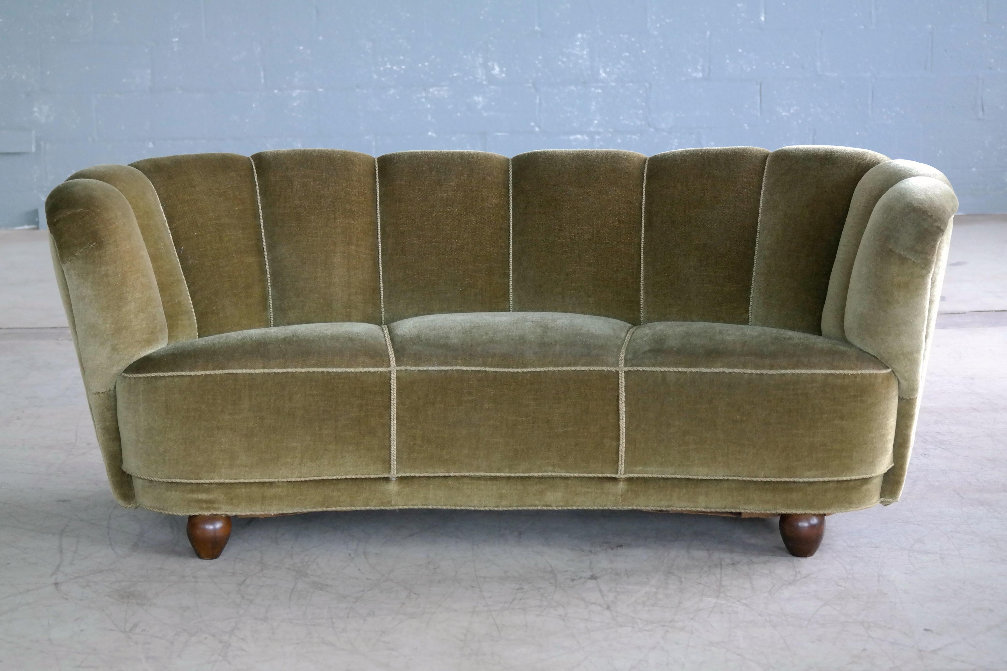 1940s Danish curved sofa often referred to by the Danes as banana form sofa. This sofa has a really nice elegant lines and we love the combination of the mohair fabric with the channels in the back. The sofa was re-upholstered at a later point and