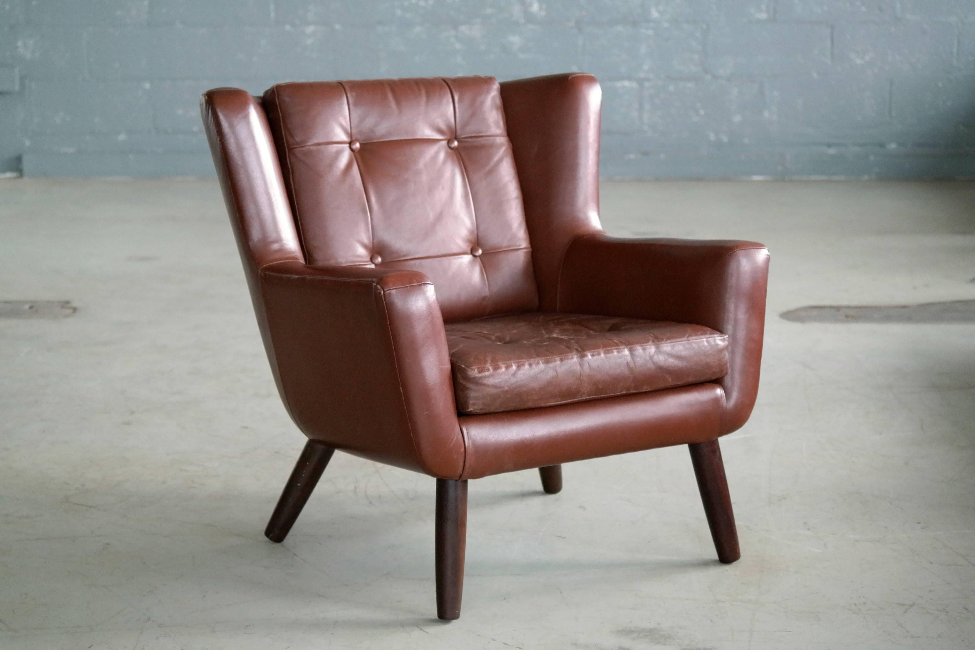 Very charming easy chairs in a nice warm chestnut brown colored leather with tufted back and seat cushion raised on solid teak legs made in the 1960s by Skjold Sørensen of Denmark. Skjold Sørensen had a unique and very characteristic design style