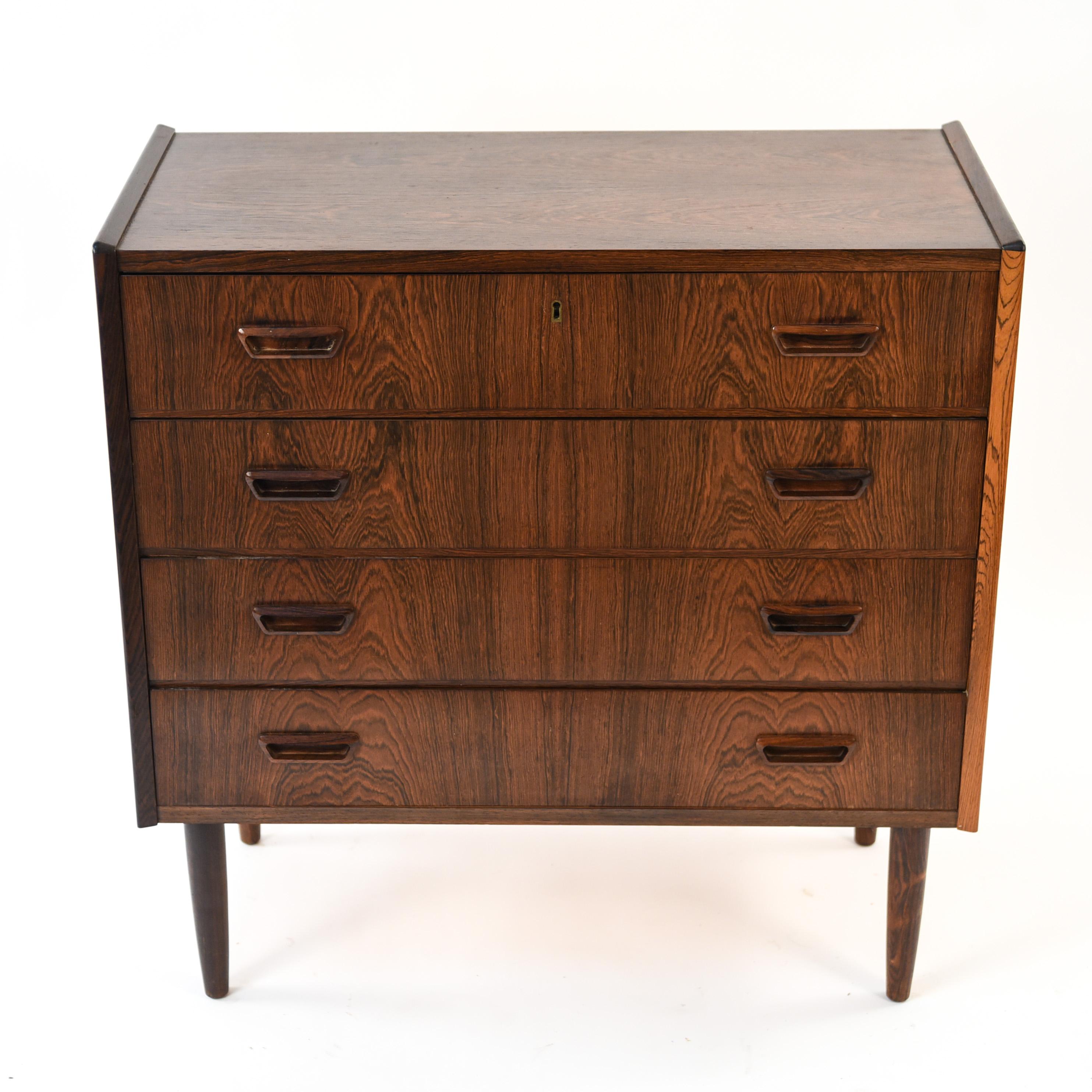 This Danish midcentury four-drawer rosewood chest would be an ideal apartment living piece due to its petite, compact size. The rich color and grain of the rosewood show the quality of this Danish Modern design.