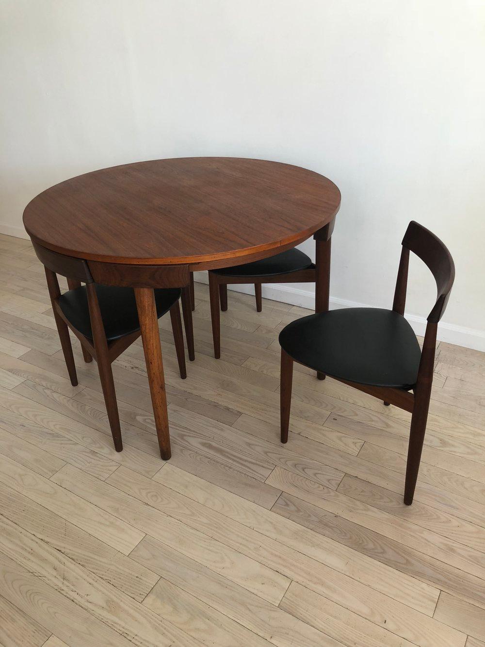 Midcentury Danish Hans Olsen for Frem Rojle teak dining table set. Four chairs that fit into the round dining table. The dining chairs are three-legged. Super rare and beautiful set of furniture. Minor break in one top section of leg that has been