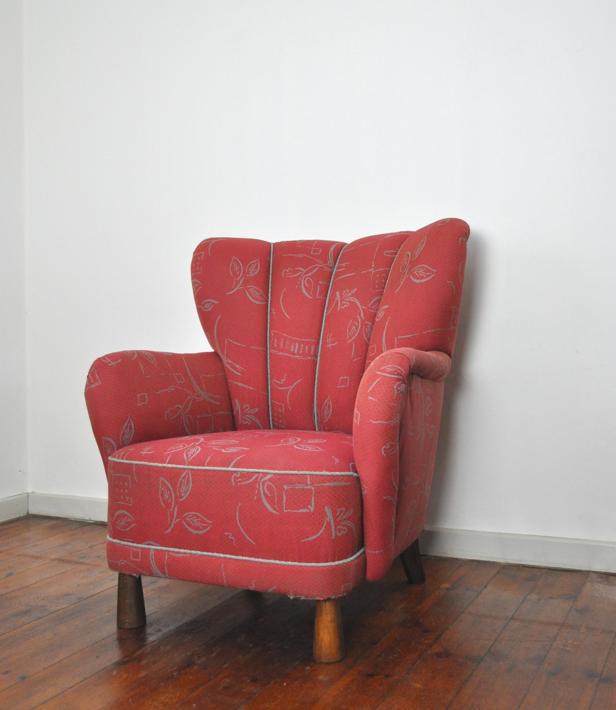 An early modernist form Danish wingback lounge chair with cone-shaped legs in the front. Over-stuffed form, enveloping the sitter with original red wool upholstery with a fine pattern typical of the period.
Contemporary to works from the 1940s by