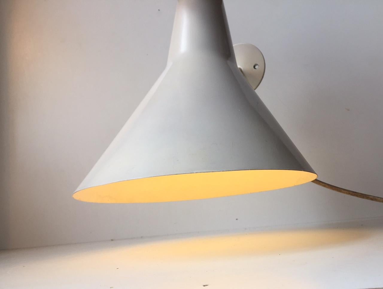 This large indoor or outdoor industrial sconce was designed and manufactured by the Danish company Fog & Mørup during the 1970s. The mount is made from steel and the shade from angle cut and shaped aluminium. The fixture is in original condition and