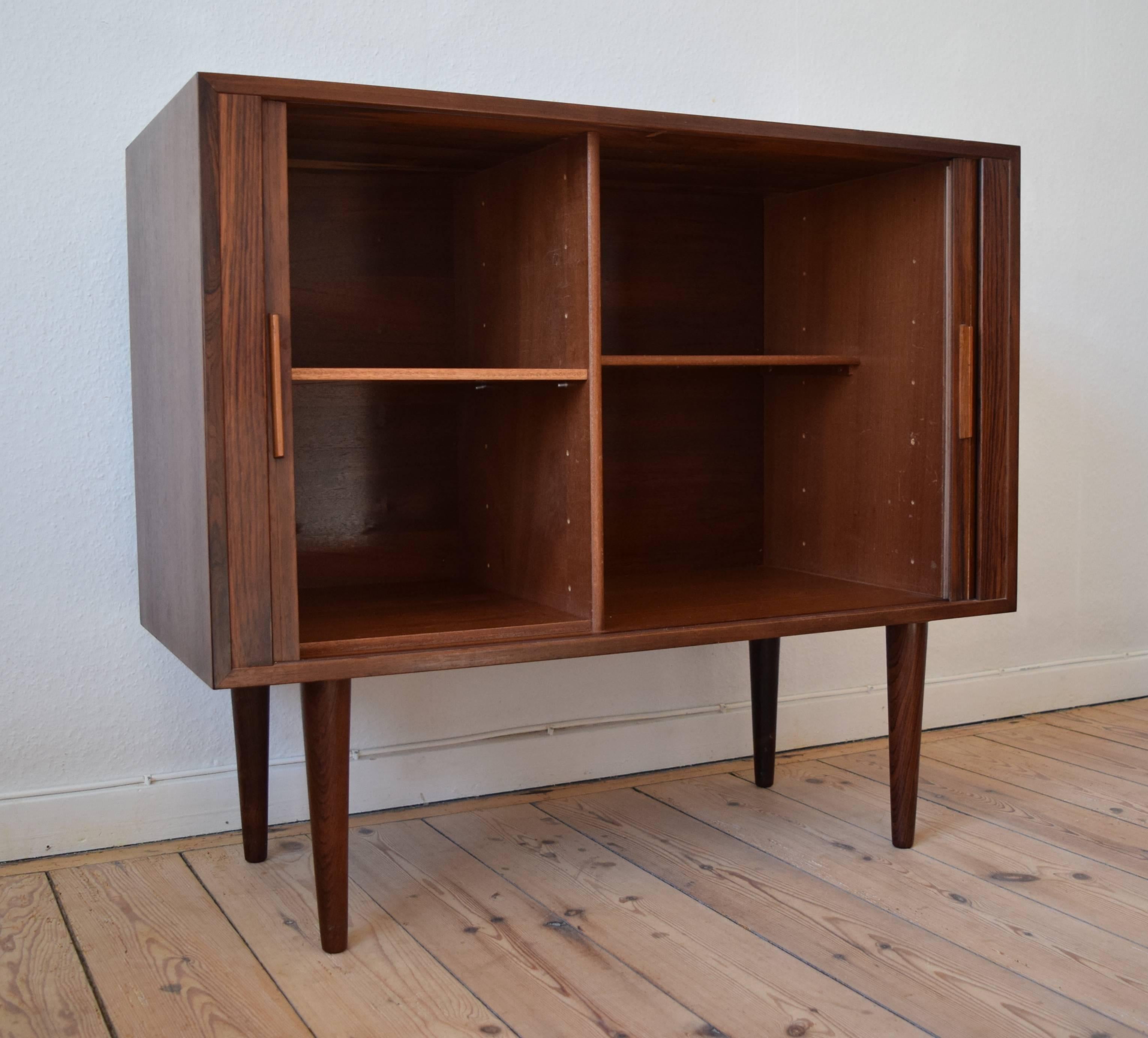 1960s Kai Kristiansen rosewood chest of drawers. Features tambour doors with solid rosewood pulls and interior shelves. The shelves can be rearranged to accommodate vertical shelf dividers which can be used for vinyl records etc, manufactured by
