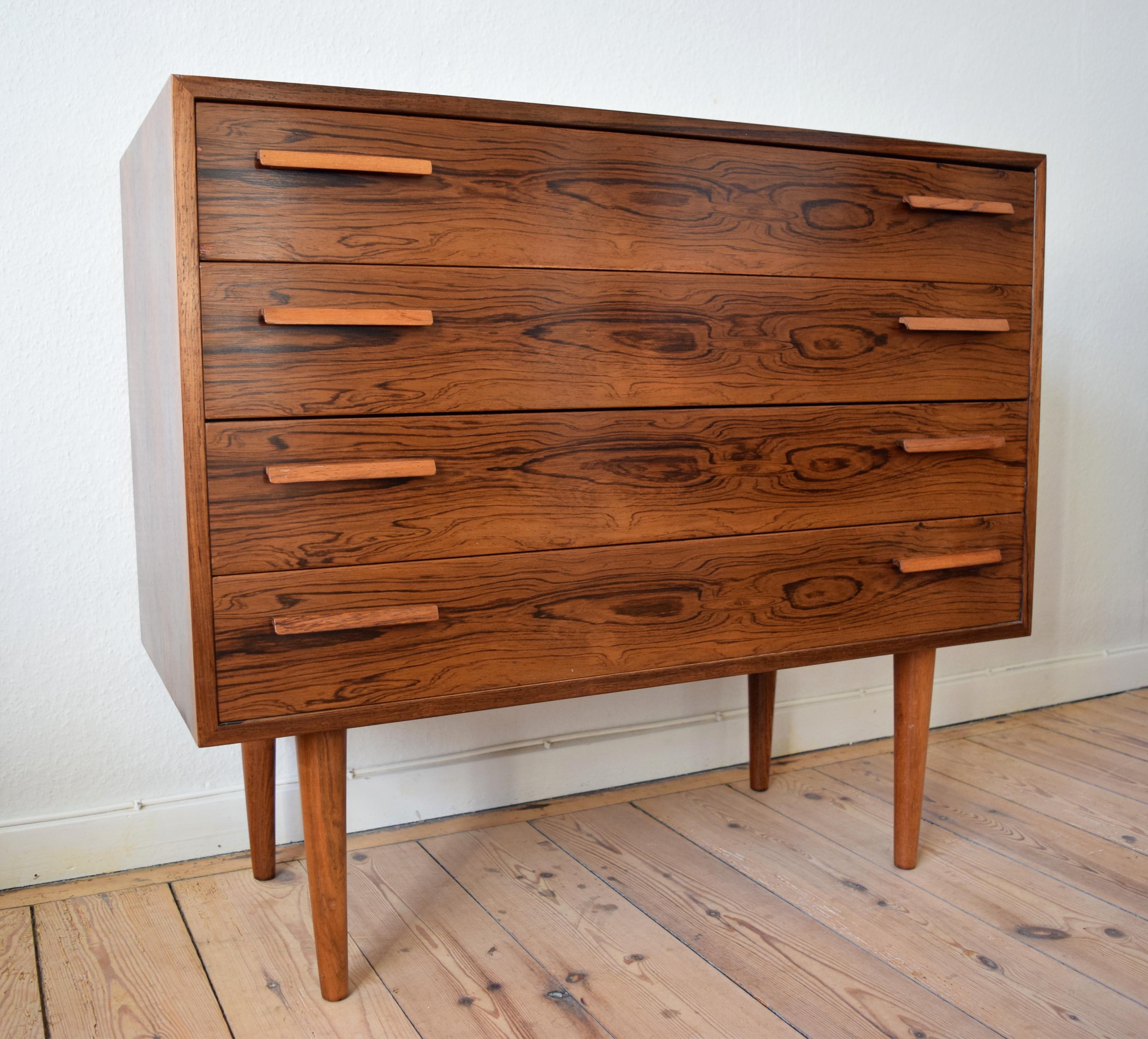 Danish rosewood chest of drawers by Kai Kristiansen for FM Møbler. Manufactured in the 1960s, this piece features four smooth sliding drawers with solid rosewood handles. Sits on turned and tapered solid rosewood legs. Striking rosewood grain