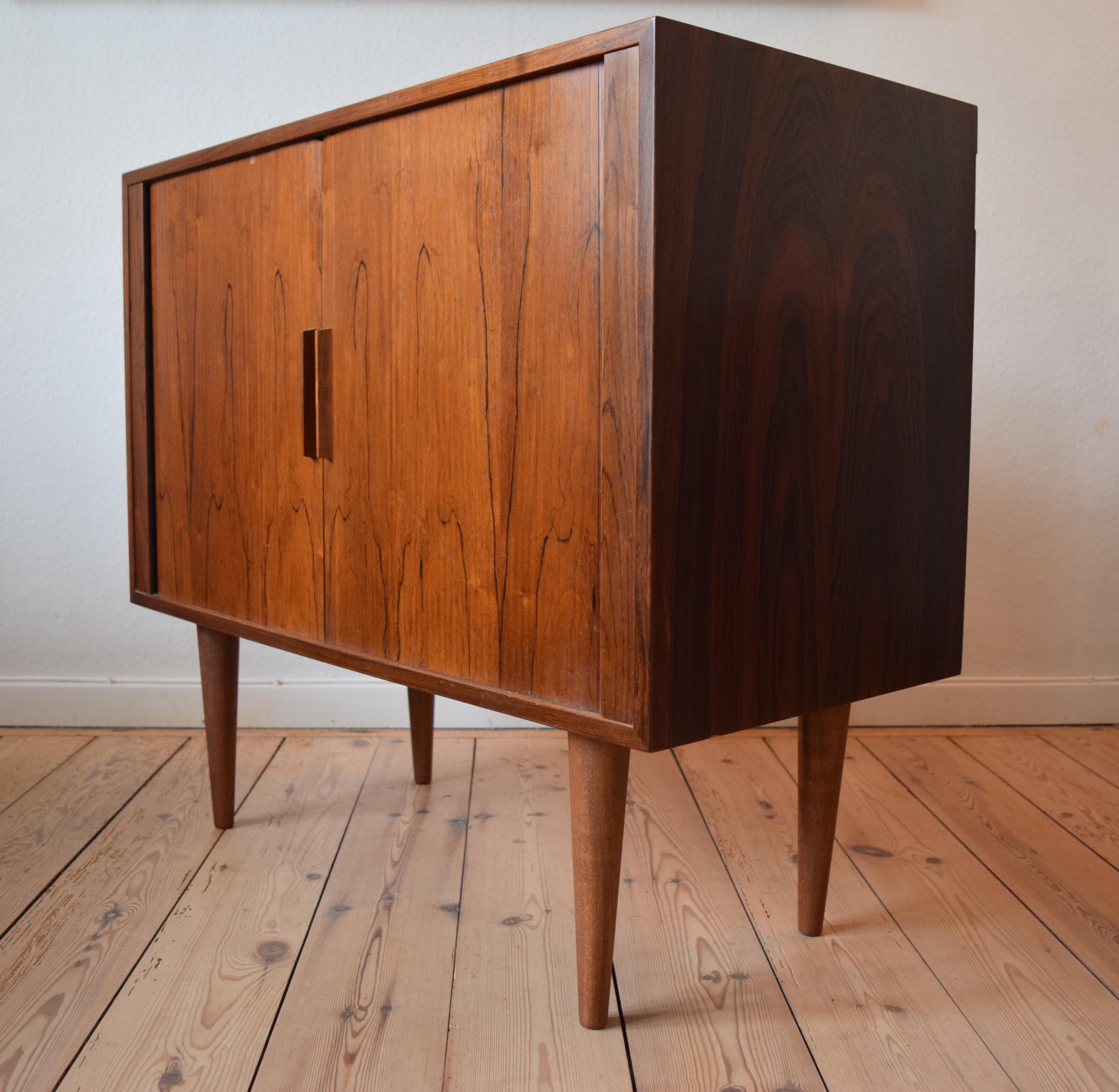 Danish rosewood cabinet by Kai Kristiansen for FM Møbler. Manufactured in the 1960s, this piece features two tambour doors with internal shelf and teak sliding drawer. Sits on turned and tapered solid rosewood legs. Striking rosewood grain