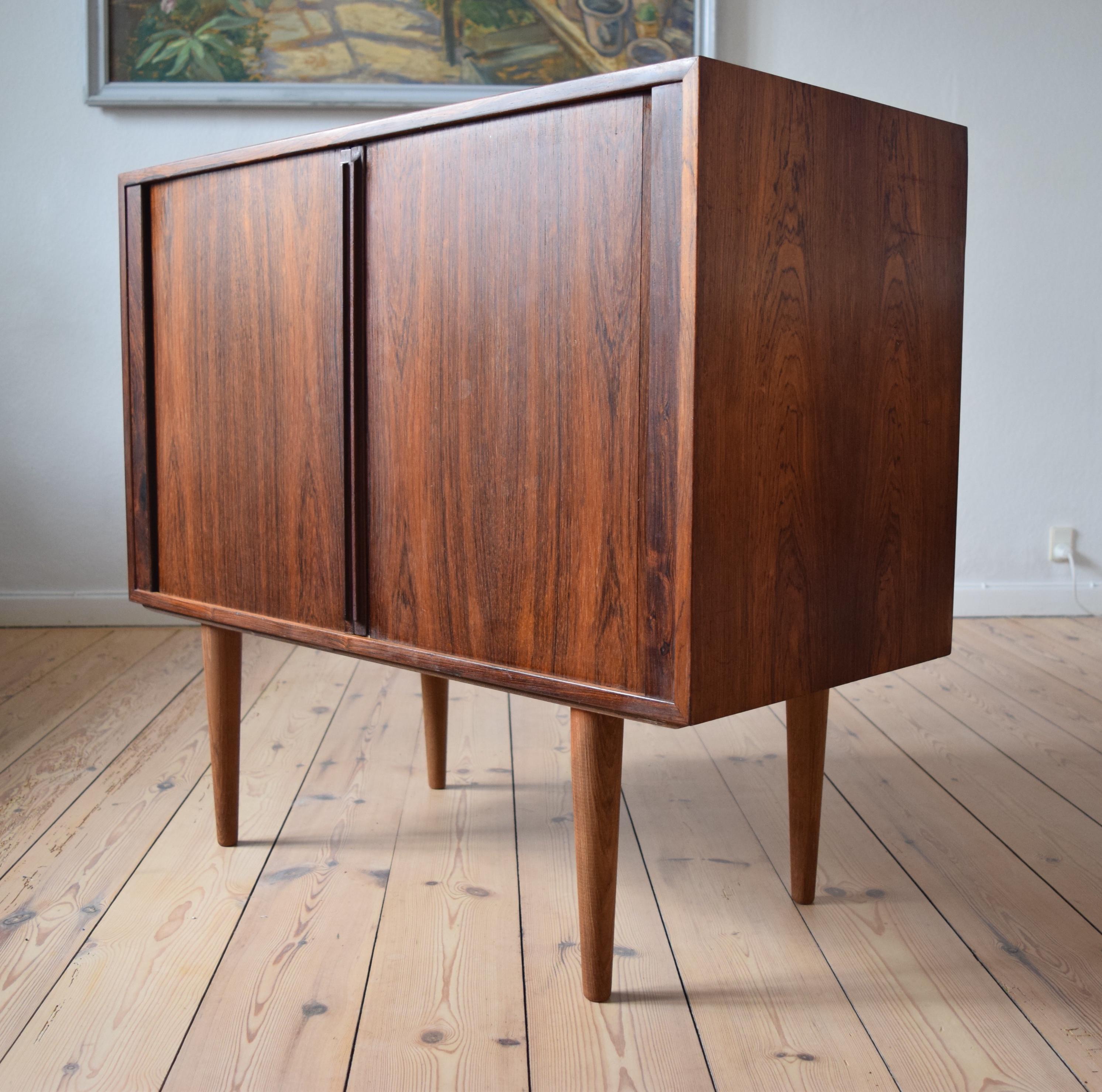 Danish rosewood cabinet by Kai Kristiansen for FM Møbler. Manufactured in the 1960s, this piece features two tambour doors with long solid rosewood handles. Internal compartment with adjustable shelf. Striking rosewood grain throughout. The unit is