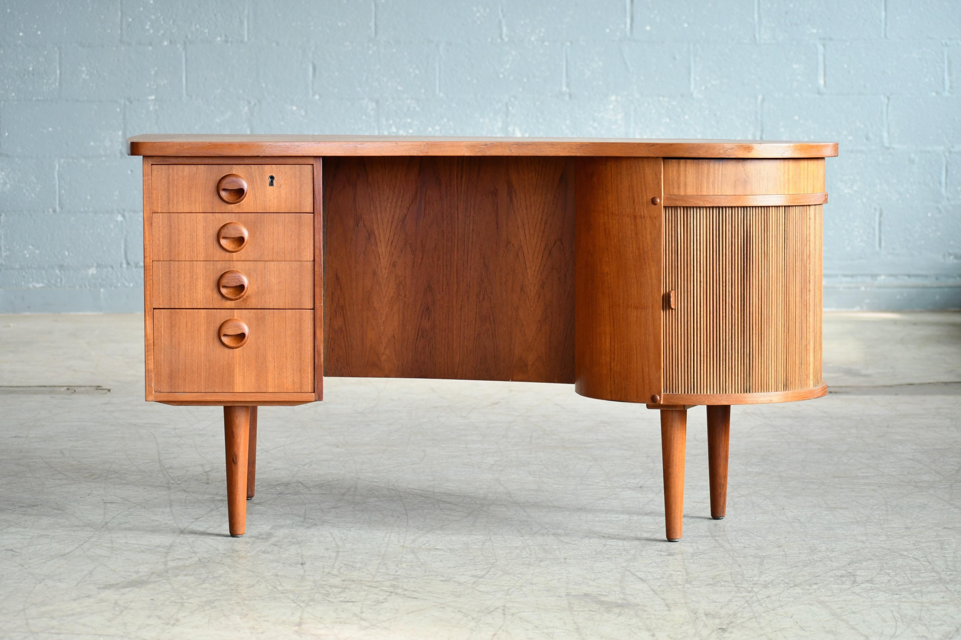 Beautiful Danish medium size executive desk in teak attributed to Kai Kristiansen and made in Denmark in the 1950s. Very organic kidney-shaped design of the top and nice carved pulls in solid teak. Versatile size fitting well into urban homes and