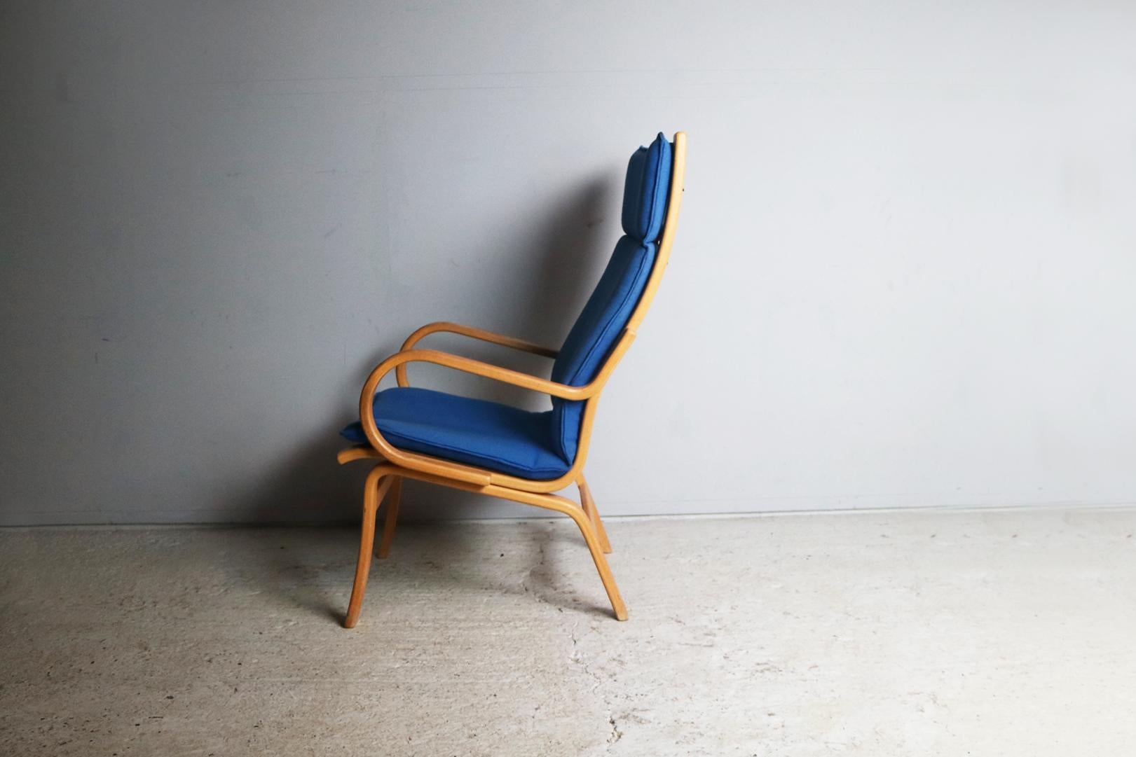 This 1970s Scandinavian lounge chair has a plain beech bentwood frame, with one a one piece woollen fabric backrest and seat cushion.

The seating is held in place by leather straps that are buckled onto the frame (see photograph).

