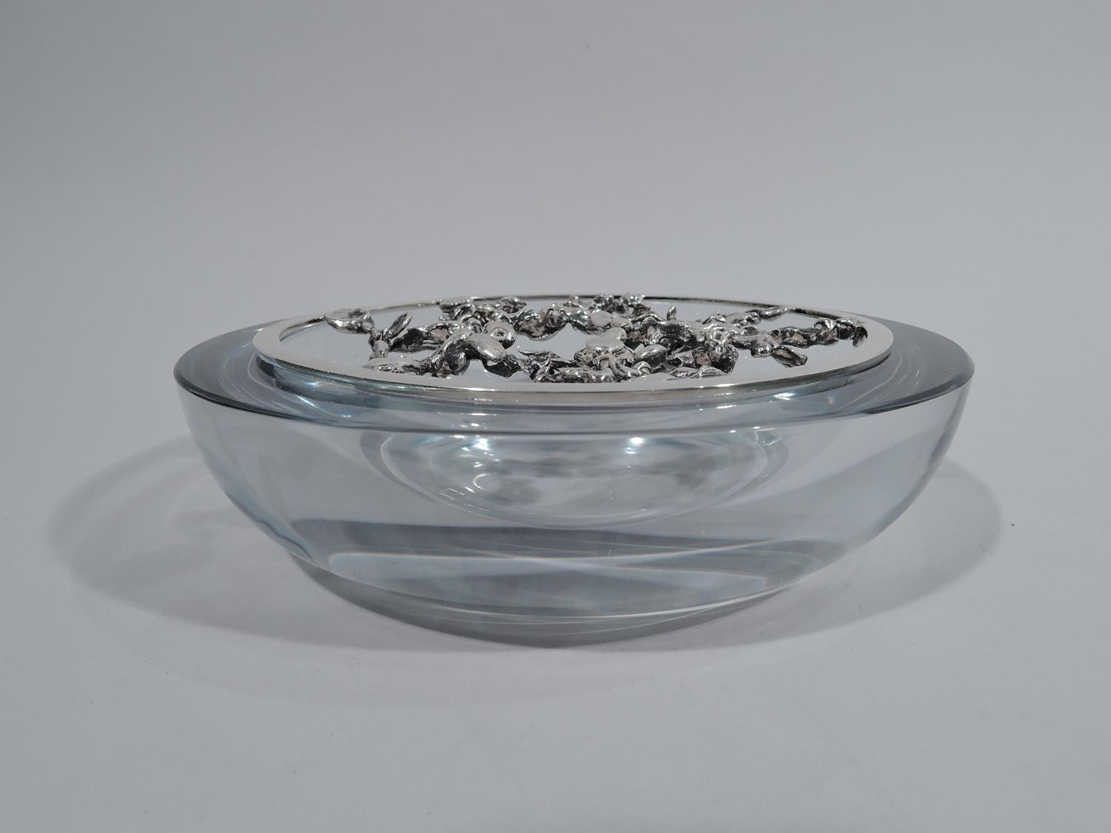 Danish modern glass and sterling silver bowl. Clear glass with curved sides and wide and flat rim. Sterling silver “frog” comprising tooled and irregular stretchers set in plain and flat round ring. Silver marked “925S” with maker’s stamp for Aage