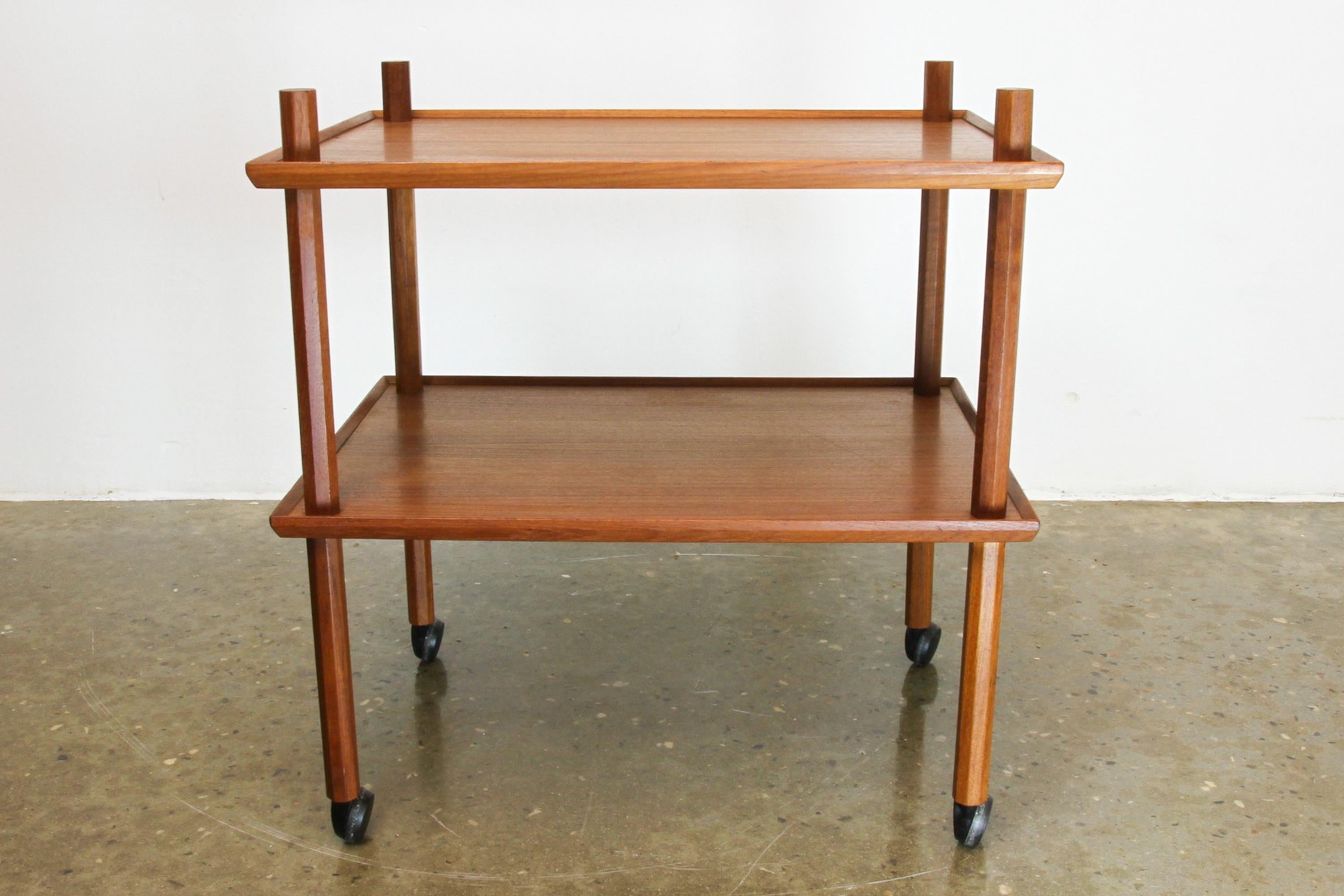 Danish Mid-Century Modern teak bar cart, 1960s.
Elegant Danish serving trolly with two large shelves in teak veneer with edges in solid teak. Four hexagonal pillars in solid teak, with original black wheels. Useful for many purposes e.g. bar