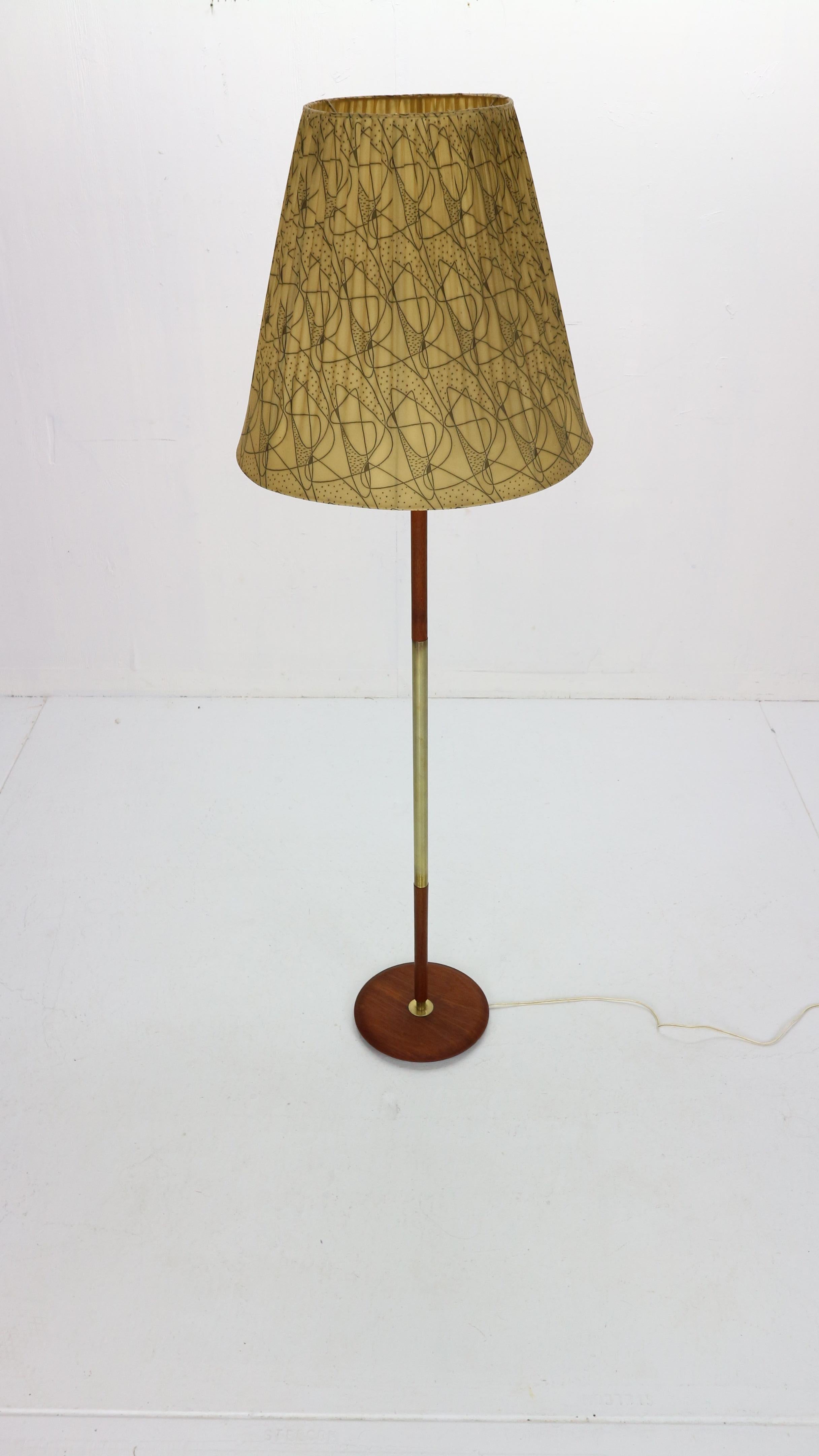 Mid-Century Modern period floor lamp is made in 1950s period, Denmark.
The lamp has a teak base combined with brass details. The switch is attached to the fitting and is typical Danish design.
The lamp shade is yellow color with ornaments.
The