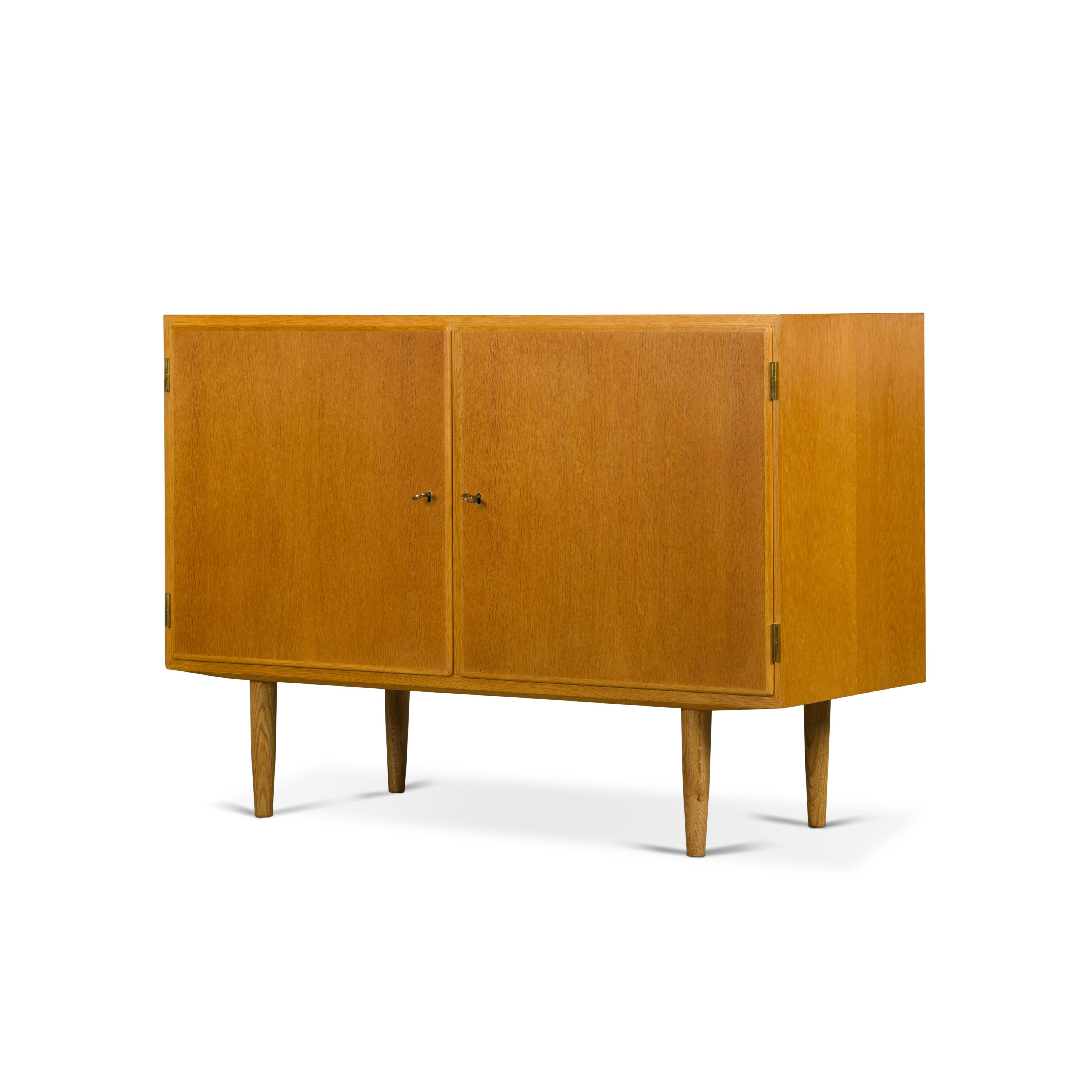 Designed by Carlo Jensen and made by Hundevad & Co. This side board is truly beautiful. Finished in an oak veneer this cabinet comes with great construction finesse and quality. There are three height adjustable drawers in beech and ash that allow