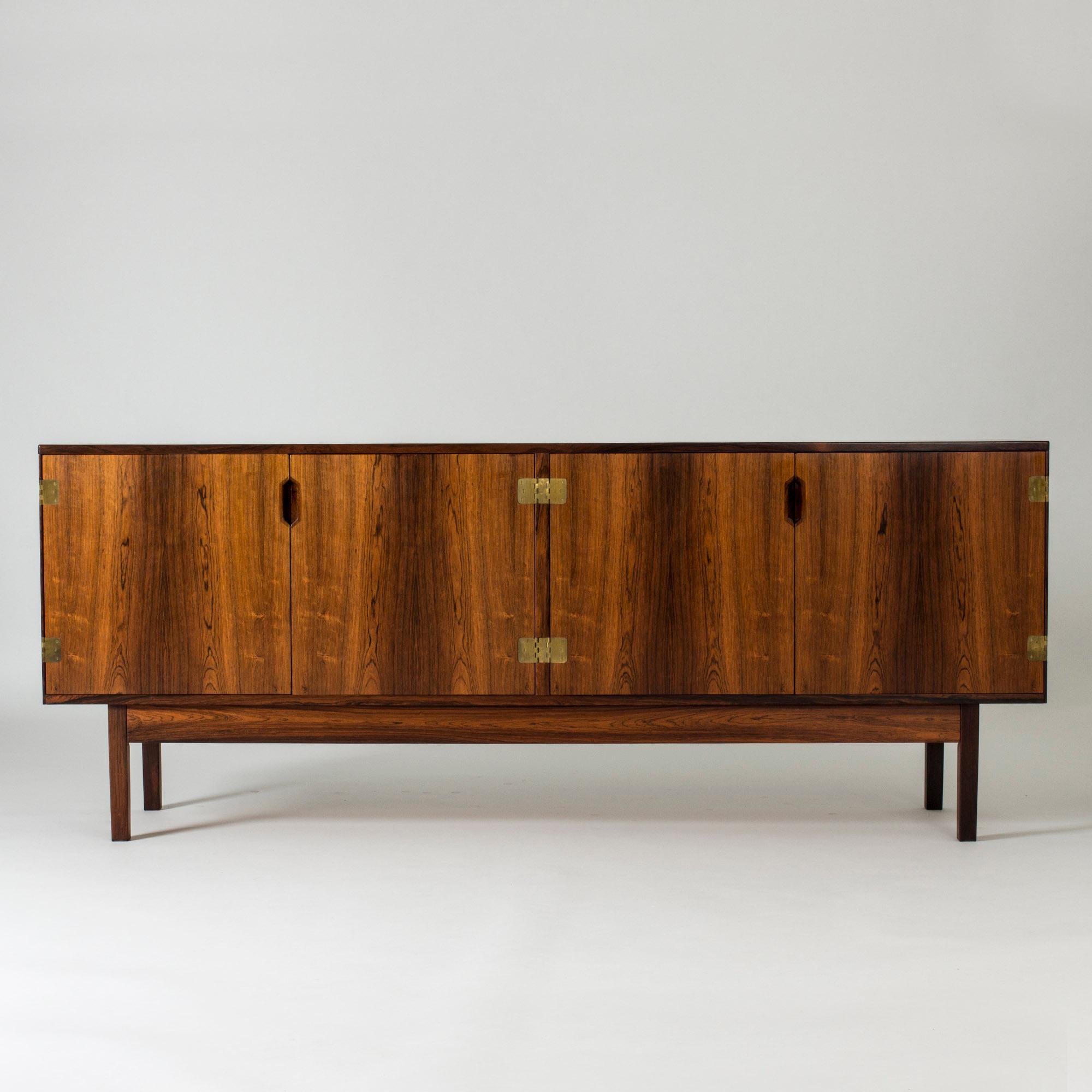 Beautiful rosewood sideboard by Svend Langkilde. Elegantly sculpted handles, large decorative brass hinges on the sides and in the center of the front.
