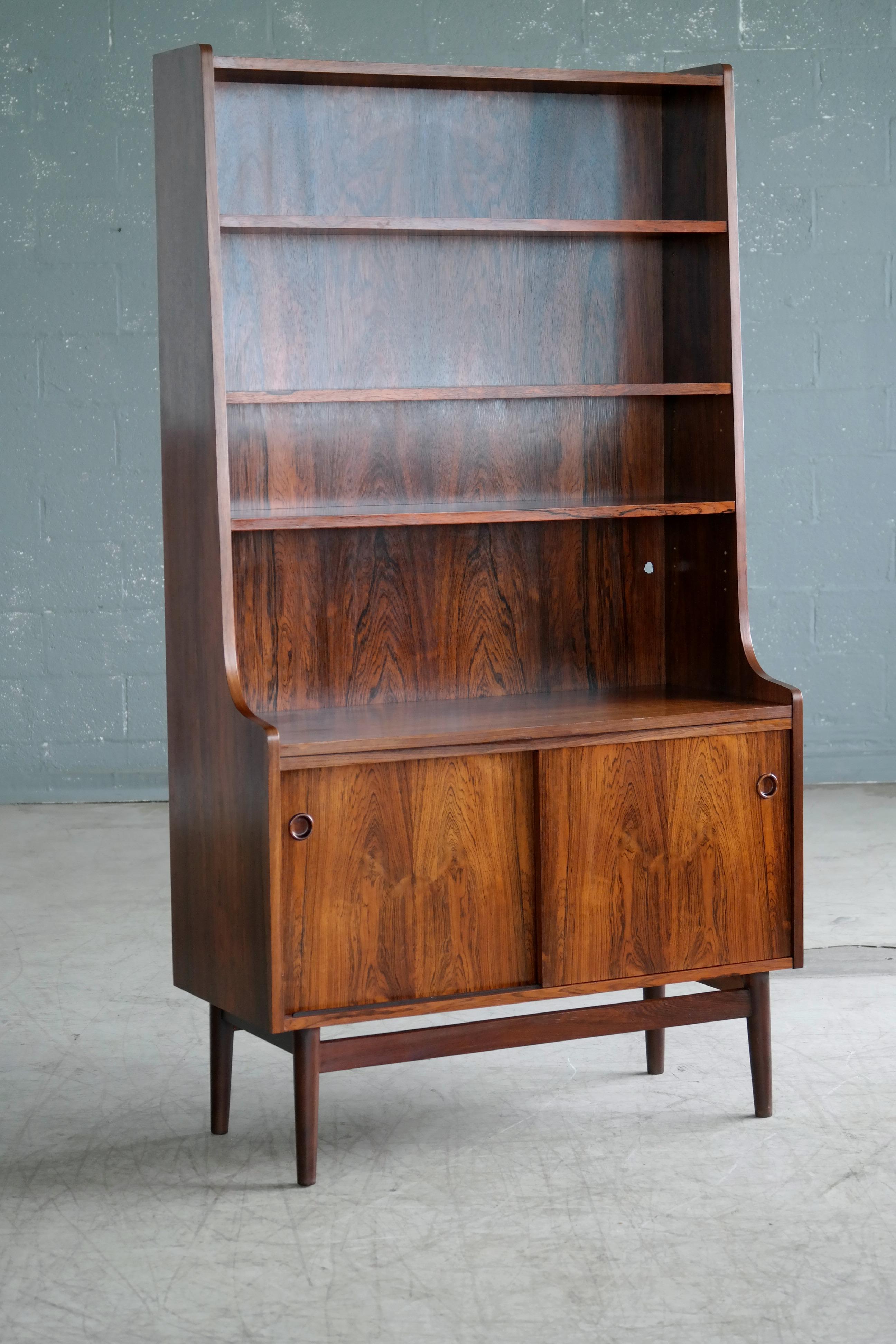 Beautiful and elegant bookcase in bookmatched rosewood with beautiful deep and dark rosewood color and rich grain. Designed by Johannes Sorth for Bornholm's Mobler also known as Nexoe Teak. Very versatile with adjustable shelves and two storage