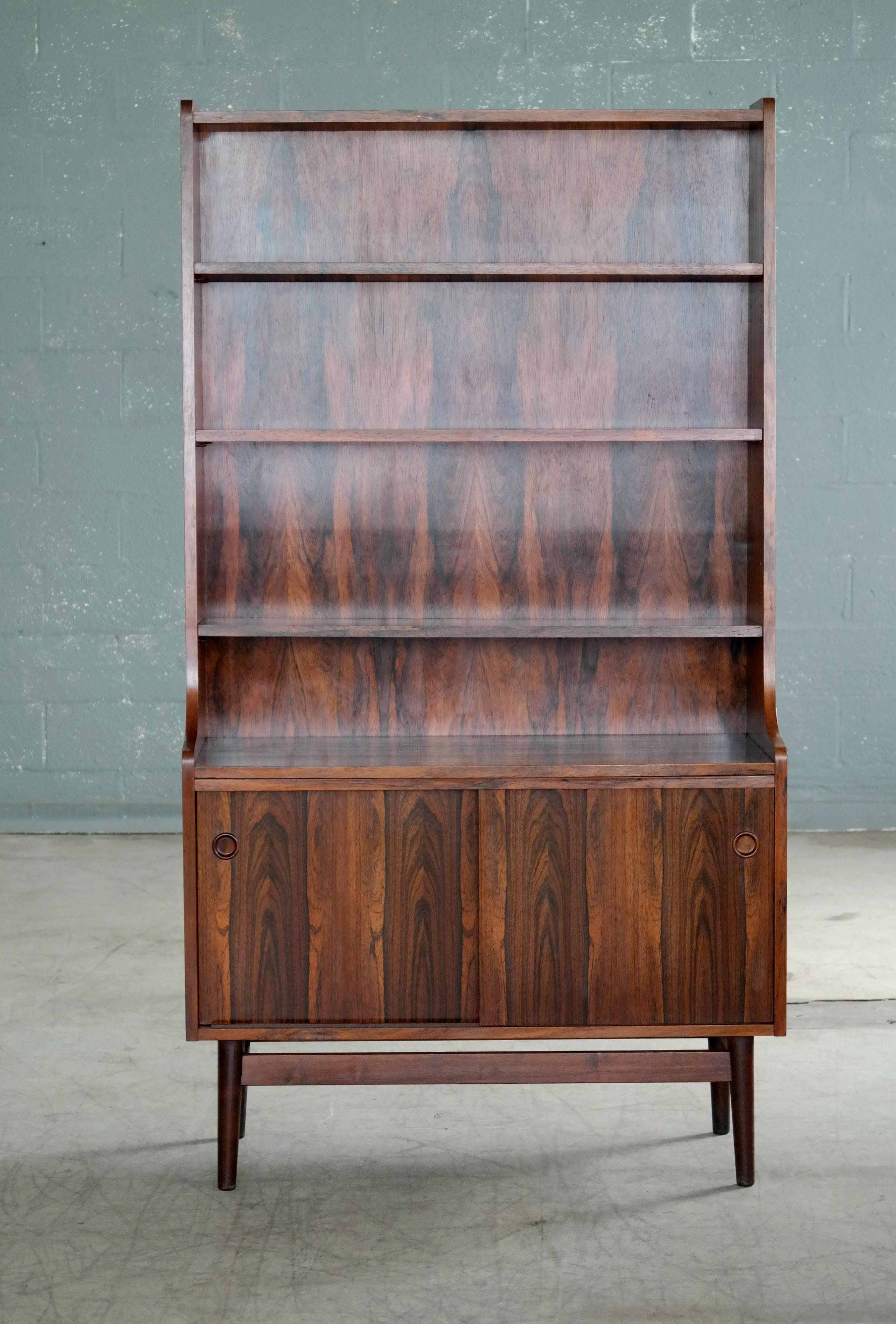 Beautiful and elegant bookcase in bookmatched rosewood with beautiful deep and dark rosewood color and rich grain. Designed by Johannes Sorth for Bornholm's Mobler also known as Nexoe Teak. Very versatile with adjustable shelves and two storage