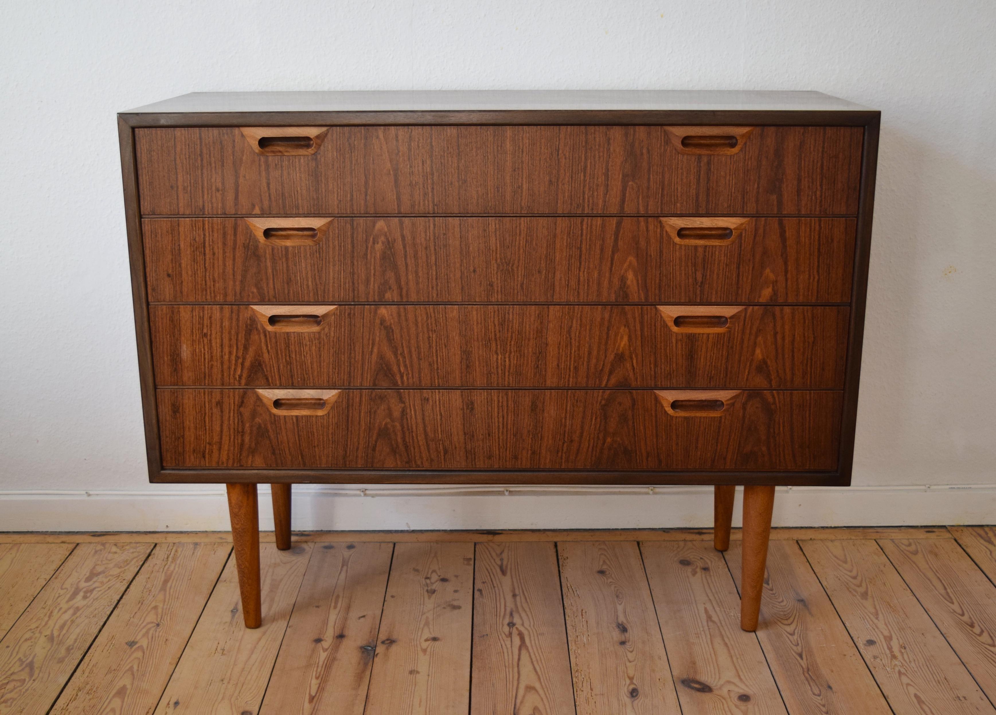4-drawer rosewood chest of drawers manufactured in Denmark in the 1960s. Features drawers with inset handles and matched rosewood grain. Very few marks. Sits on tapered splayed legs.
 
