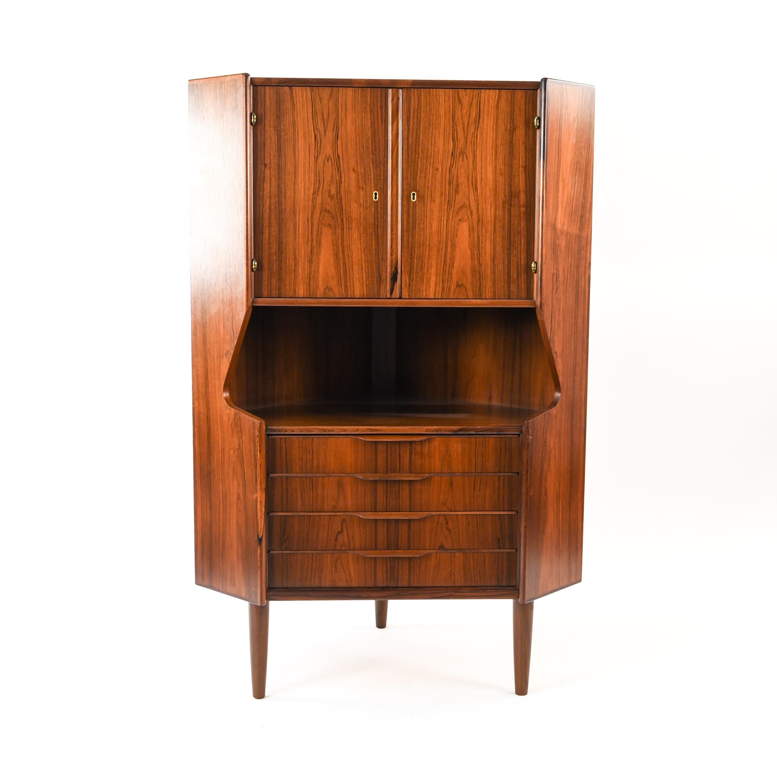 This Danish midcentury rosewood corner cabinet is full of storage with a two door cabinet on top and four drawers below. This cabinet features great modern design which is exemplified in the angularity of the sides.