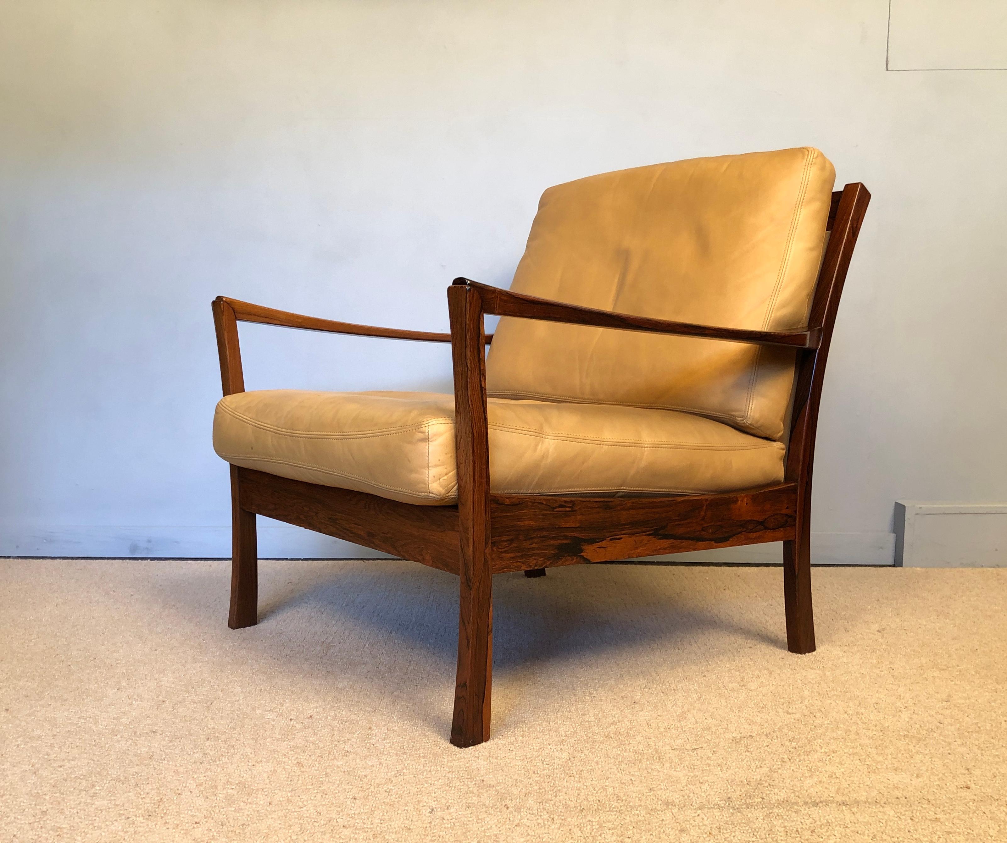 A Danish midcentury rosewood lounge chair. Unique and very unusual design with complex sculpted arm joints and tapered curves to the legs. An accomplished Scandinavian craftsman piece. Lovely rosewood frames with curved detail to the tan leather