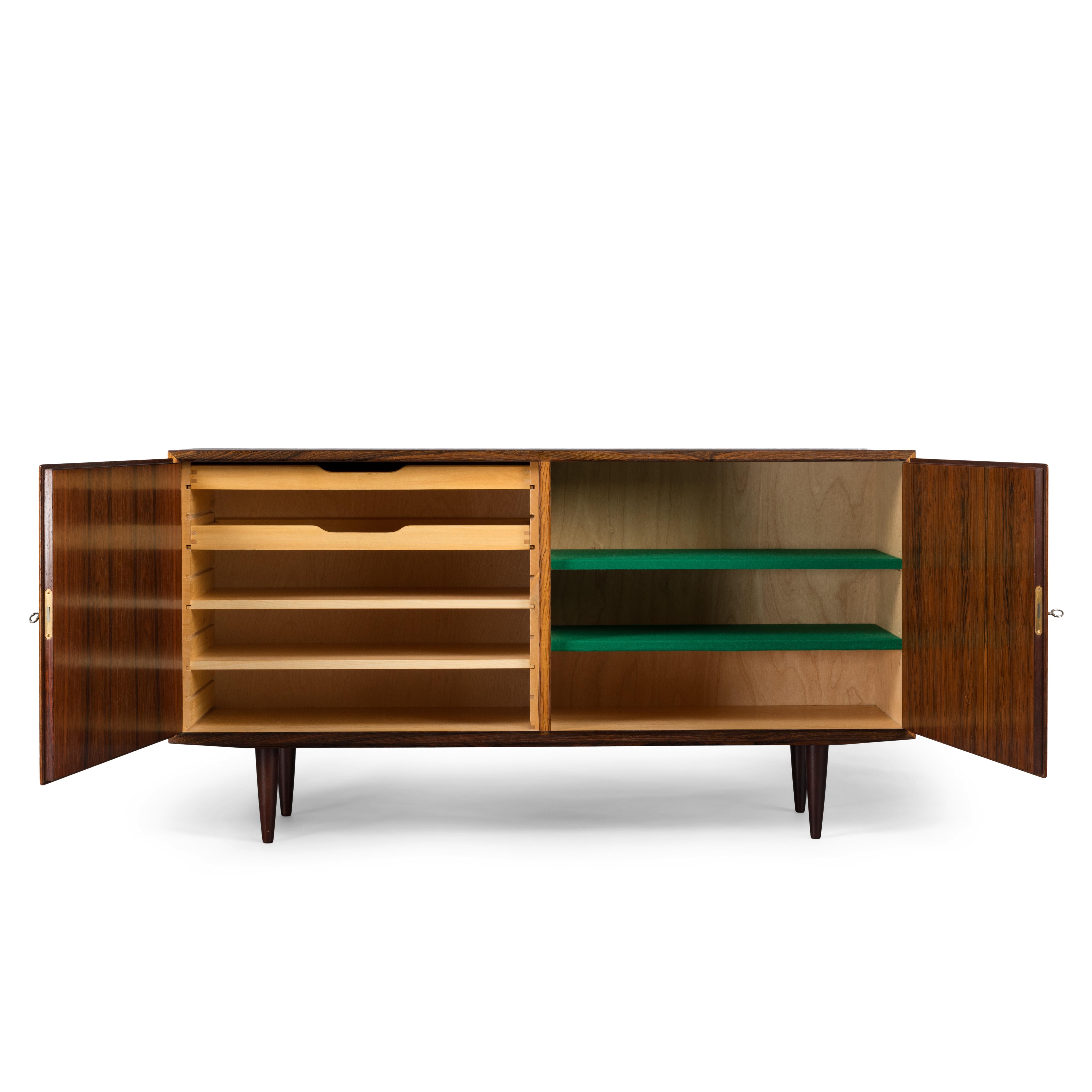 Designed by Carlo Jensen and made by Hundevad & Co. This side board is truly a Classic design. Finished in a beautiful veneer this cabinet comes with great construction finesse and quality. There are height adjustable drawers on the left hand side