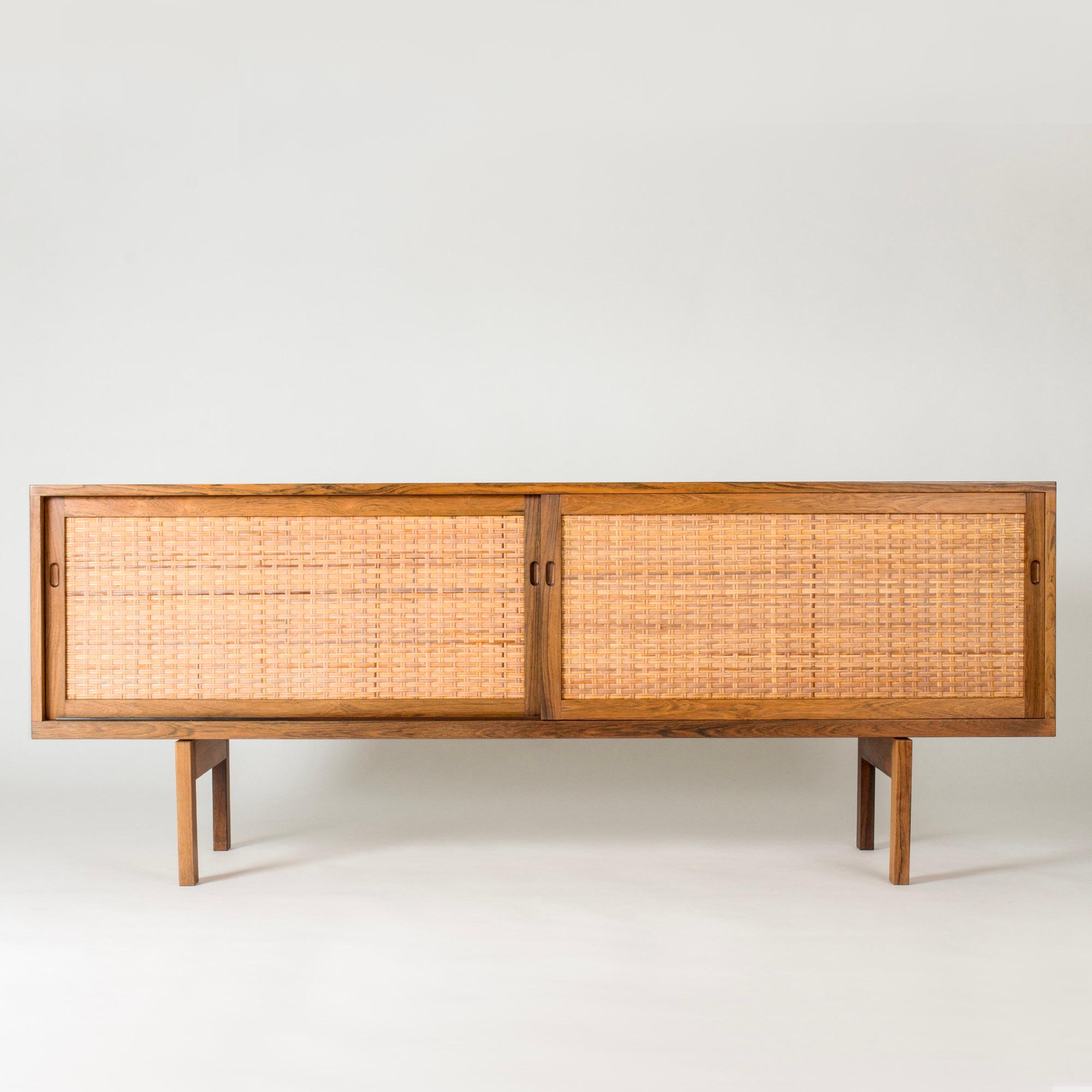 Amazing sideboard by Hans J. Wegner, model “RY-26”, made from rosewood with elegantly contrasting rattan fronts. Glass shelves to one side of inside the sideboard.